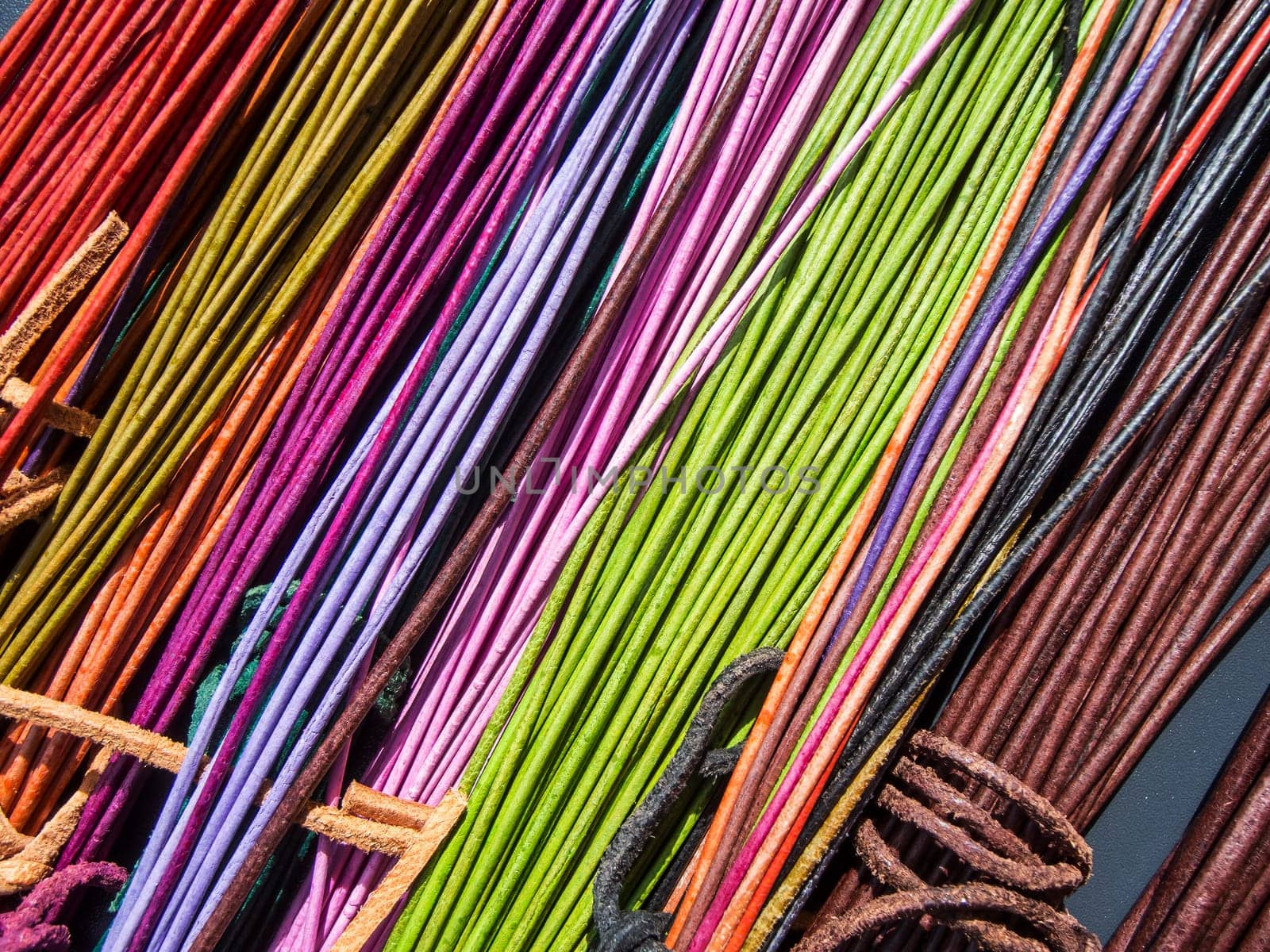 Red and orange colored leather cords with knots on a table in the sunlight in an oblique view.