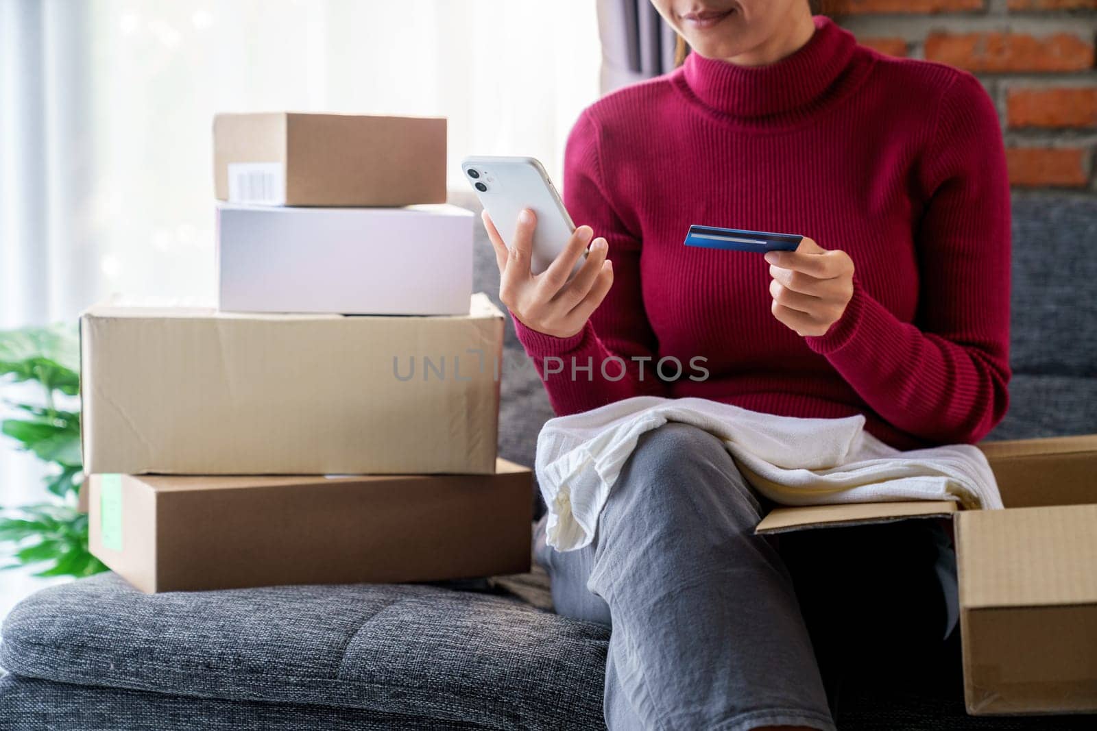 A woman holding phone and using credit card place an order shopping online