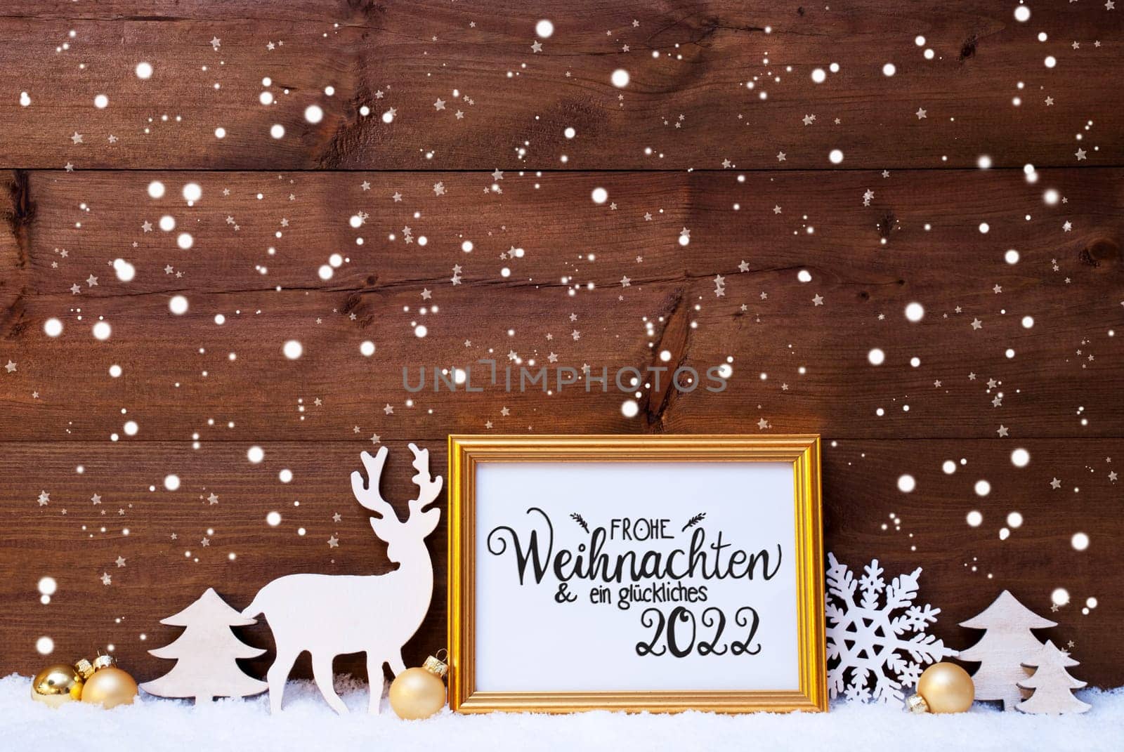 Frame With German Calligraphy Frohe Weihnachten Und Ein Glueckliches 2022 Means Merry Christmas And A Happy 2022. Golden Decoration Like Ball, Tree And Deer. Wooden Background With Snow And Snowflakes