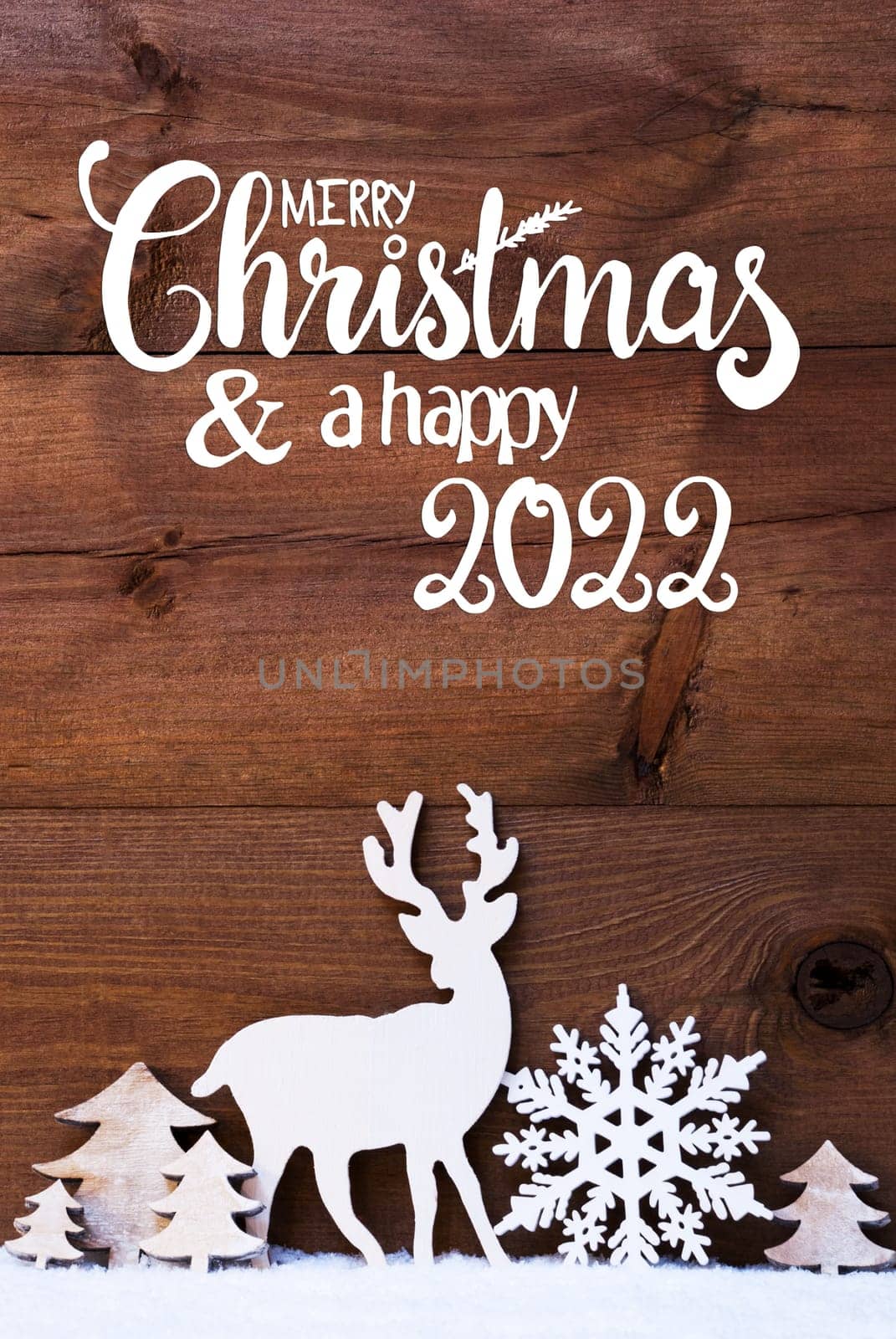 English Calligraphy Merry Christmas And Happy 2022. Christmas Decoration Like Snowflake, Tree And Deer. Brown Wooden Background