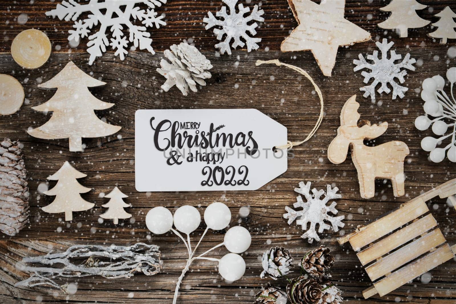 One White Label With English Text Merry Christmas And A Happy 2022. Frame Of Christmas Decoration Like Tree, Sled, Star And Fir Cone. Wooden Background With Snowflakes