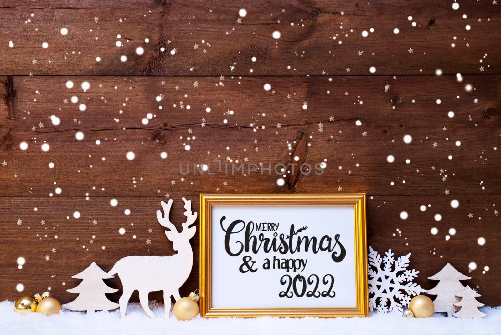 Frame With English Calligraphy Merry Christmas And A Happy 2022. Golden Decoration Like Ball, Tree And Deer. Wooden Background With Snow And Snowflakes
