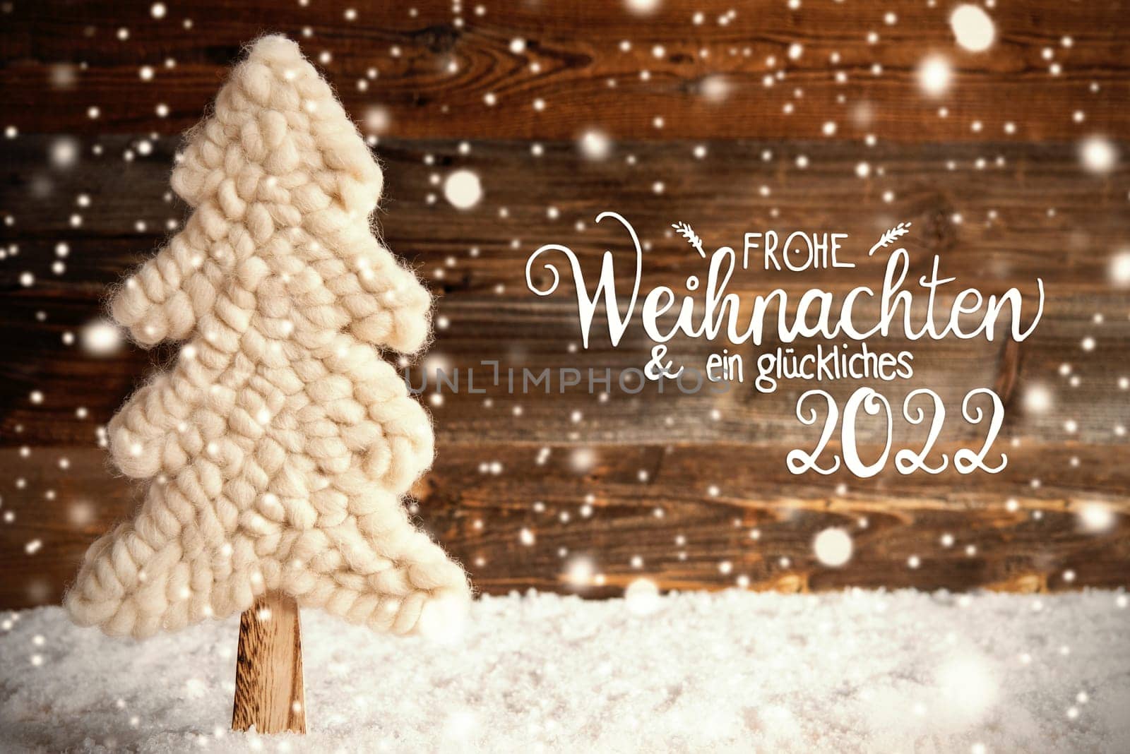 German Calligraphy Frohe Weihnachten Und Ein Glueckliches 2022 Means Merry Christmas And A Happy 2022. White Fabric Christmas Tree With Snow. Brown Rustic Wooden Background With Snowflakes