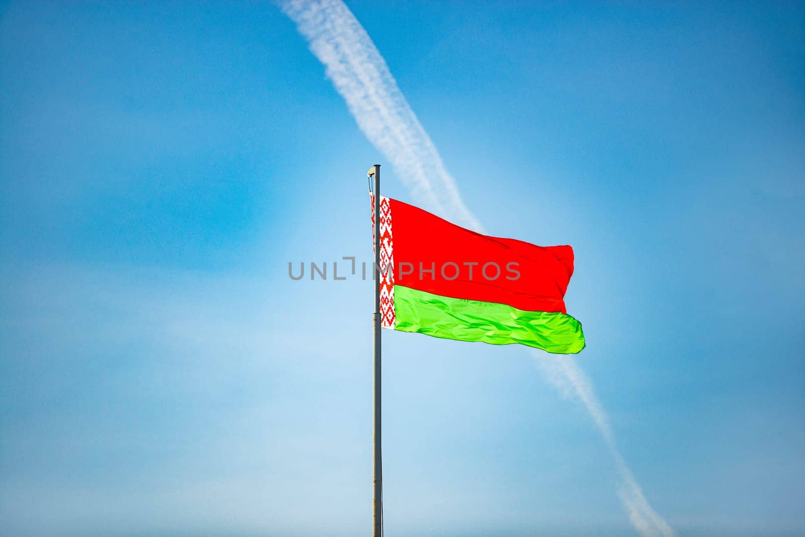 Flag of Belarus waving against blue sky without clouds