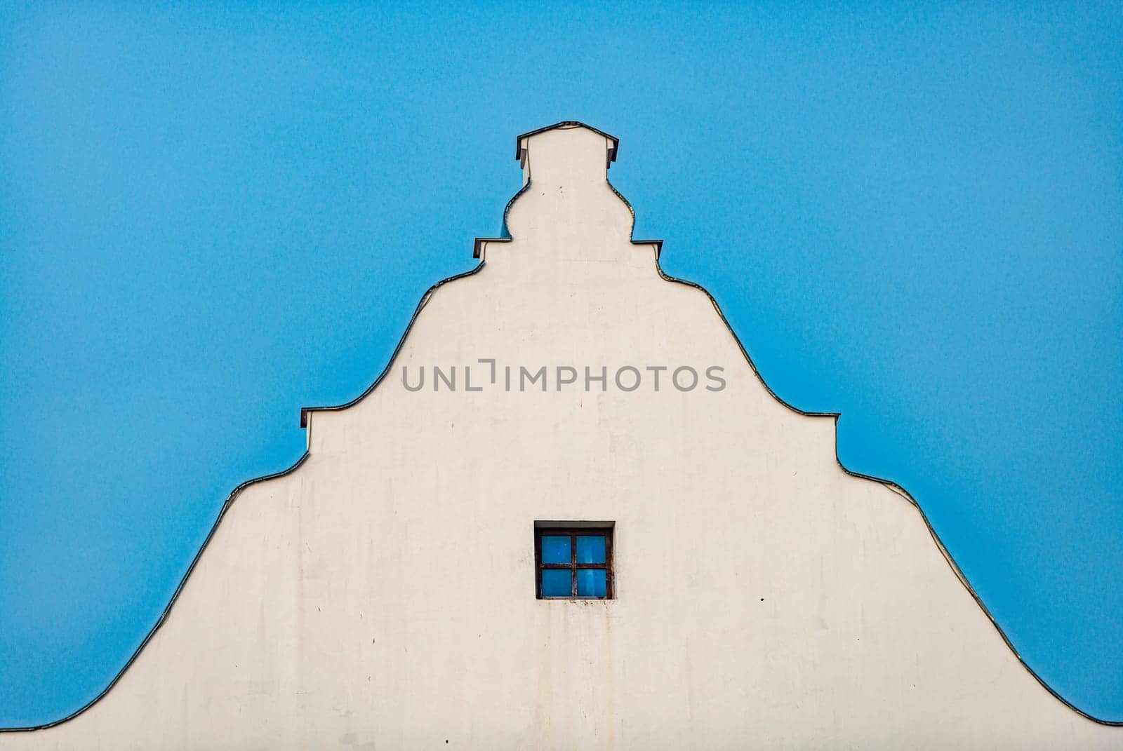 Old building roof and wall with blue sky in background