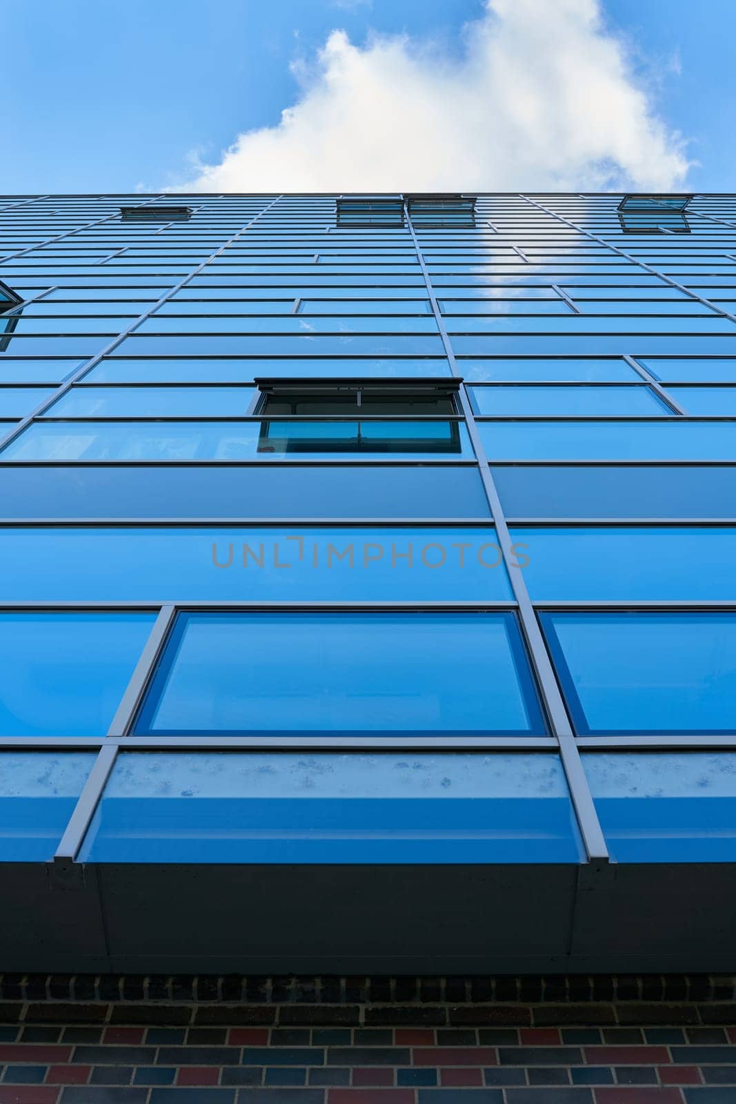 View upwards at the glass facade of a modern office building in Berlin with reflection of blue sky