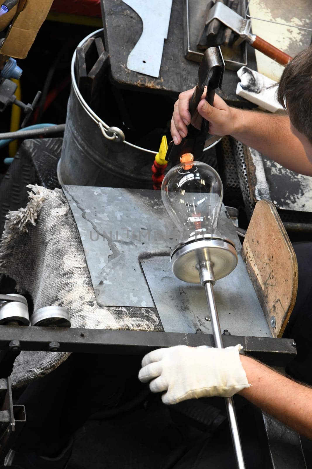 A glassblower shaping and making a drinking glass.