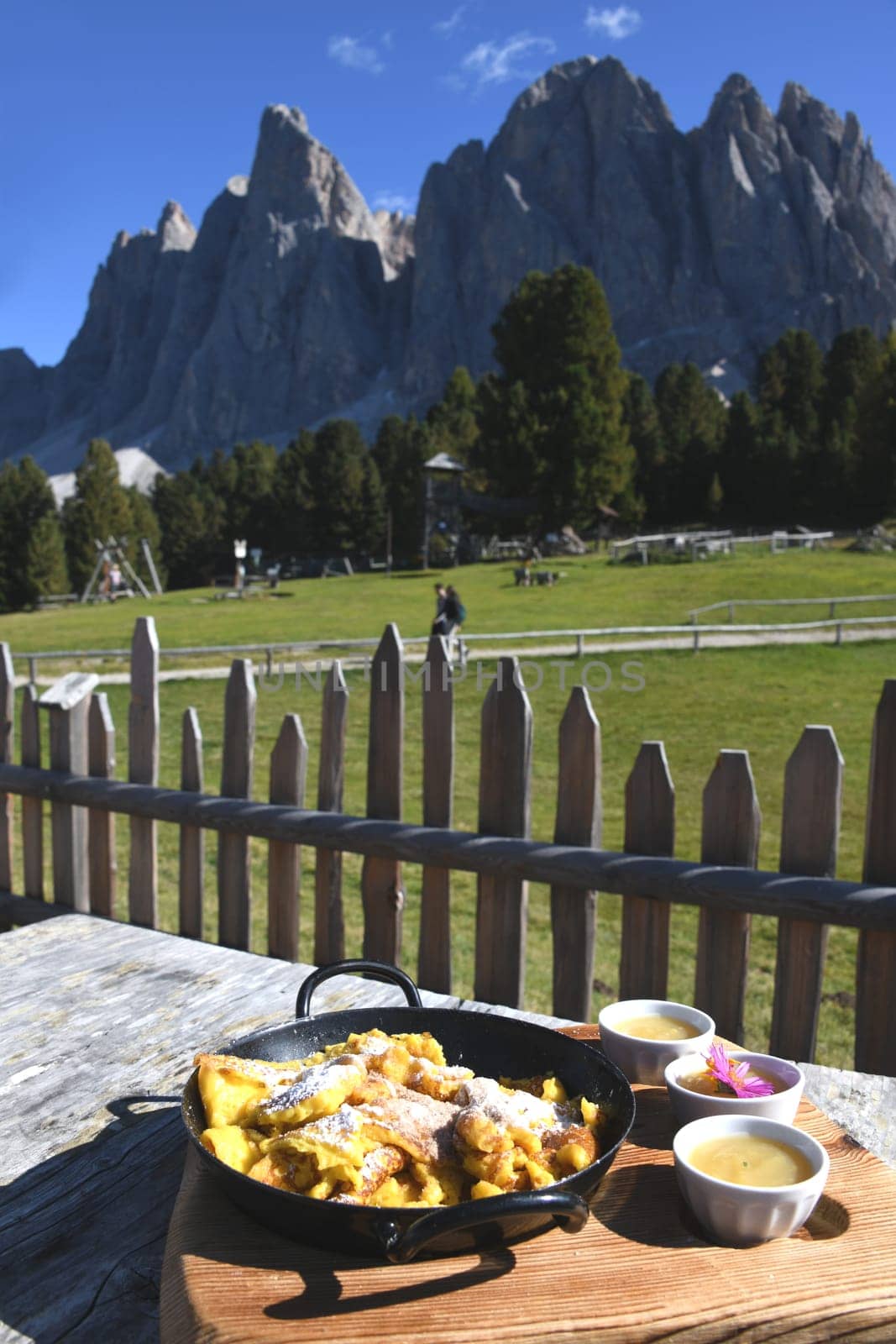 The Kaiserschmarrn is a pastry. It is one of the desserts in Austrian cuisine. It is served here with icing sugar,apple sauce and raisins in front of the Geisler peaks in the Dolomites of Italy.