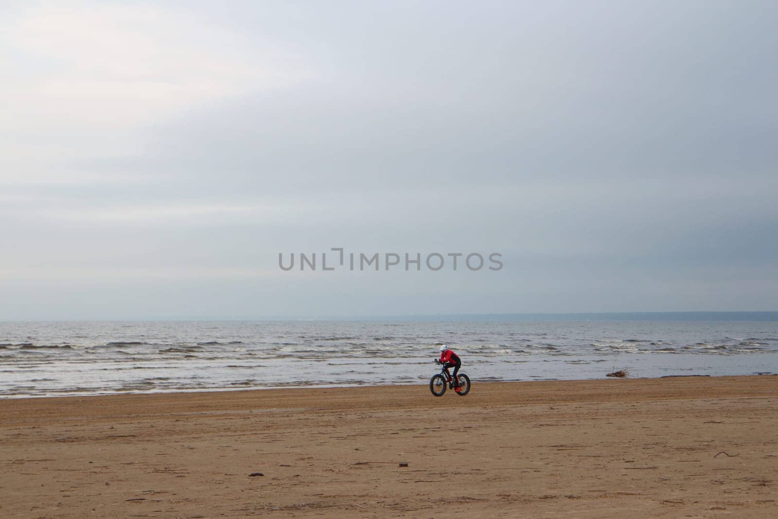 cyclist rides a fat bike on a deserted sandy beach in autumn