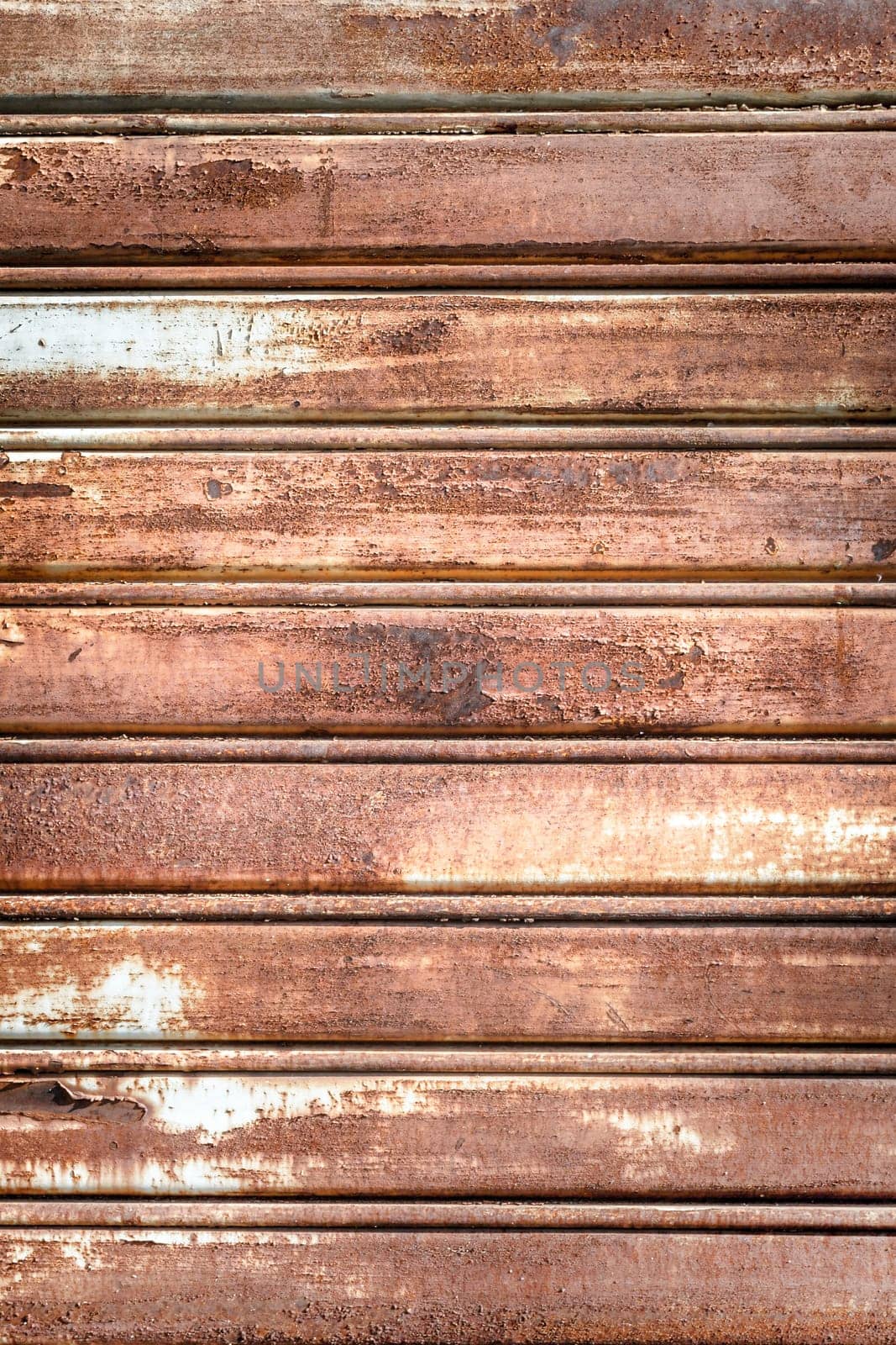 Metal shutter with peeling paint. Front view of a shutter rusted, deteriorated from elements. Ideal use for background / wallpaper.