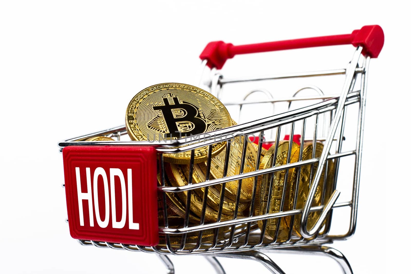 side view closeup cryptocurrency concept of market shopping cart full of bitcoin golden crypto coins with word hodl written on front isolated on white background