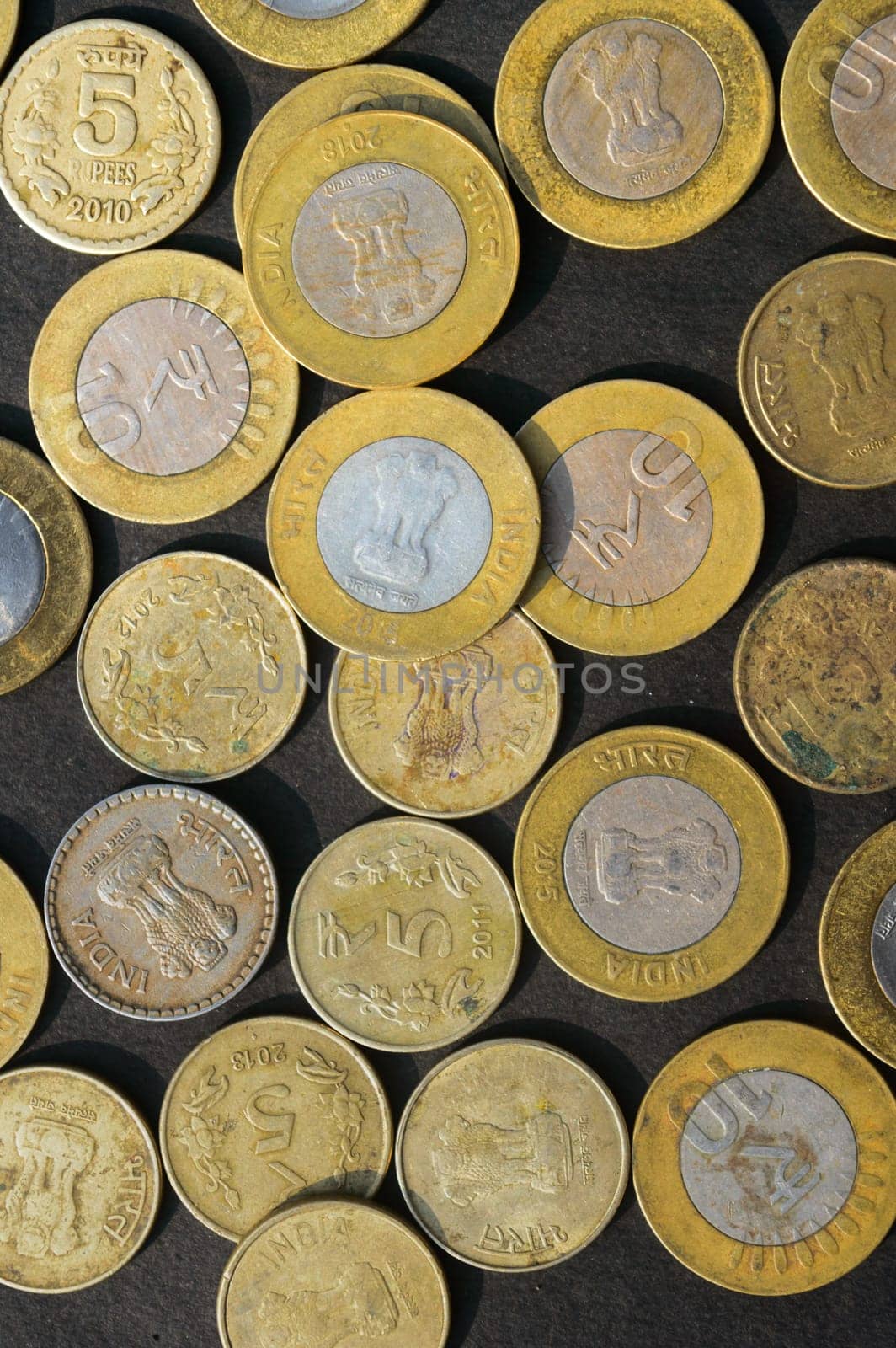 Mix of Gold Colored Indian Rupee Coin currency on rustic floor. Full Frame. Table Top View. Vertical. Business Finance and financial Investment Background. Close Up
