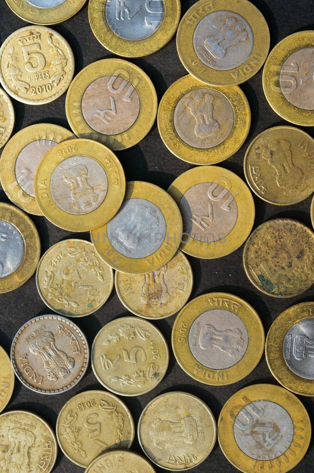 Mix of Gold Colored Indian Rupee Coin currency on rustic floor. Full Frame. Table Top View. Vertical. Business Finance and financial Investment Background. Close Up