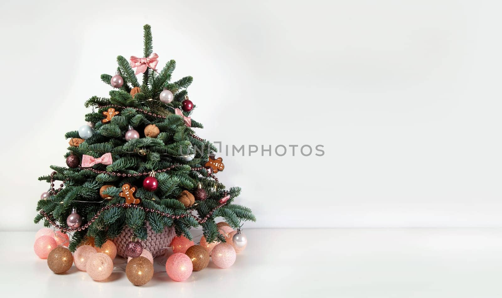 Beautiful small decorated Christmas tree on a white wooden table. Good mood. Danish pine and fir, Nobilis