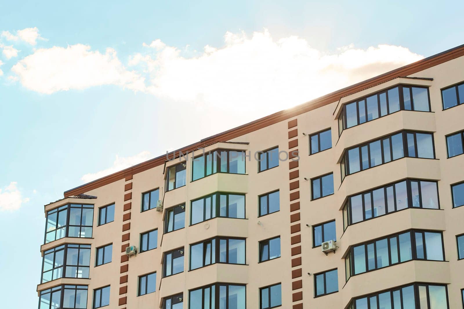 View of modern sand stucco facade with big bay window balcony and casement solid glass windows. New residential apartment condominium type. Block of flats. City real estate. Simple condo architecture
