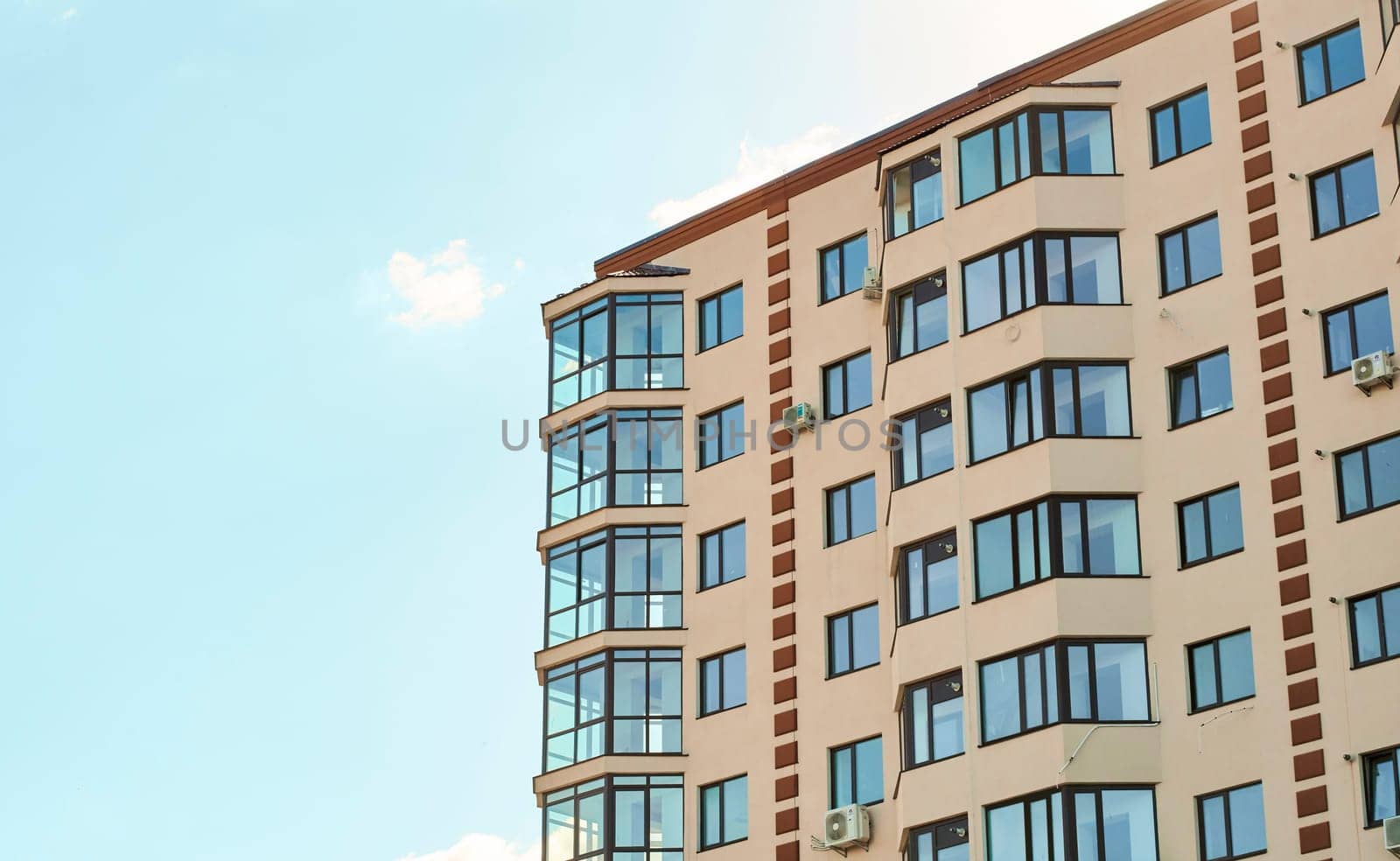 New residential apartment condominium type. View of modern sand stucco facade with big bay window balcony and casement solid glass windows. Block of flats. City real estate. Simple condo architecture