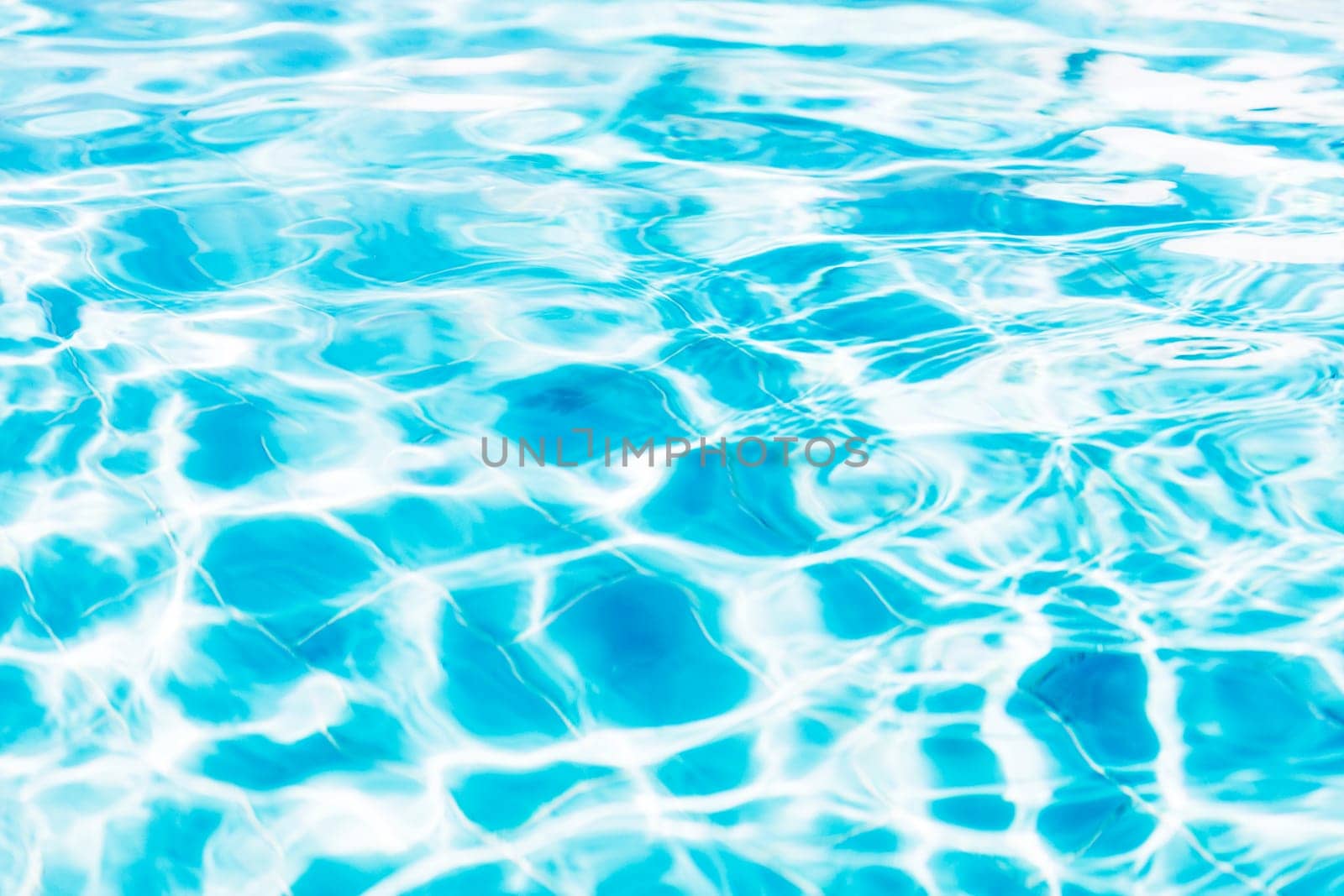 Vibrant blue white swimming pool ripped water surface with waves and nice sun sparkles. Conceptual abstract texture background. Travel or vacation summer concept. High quality photo