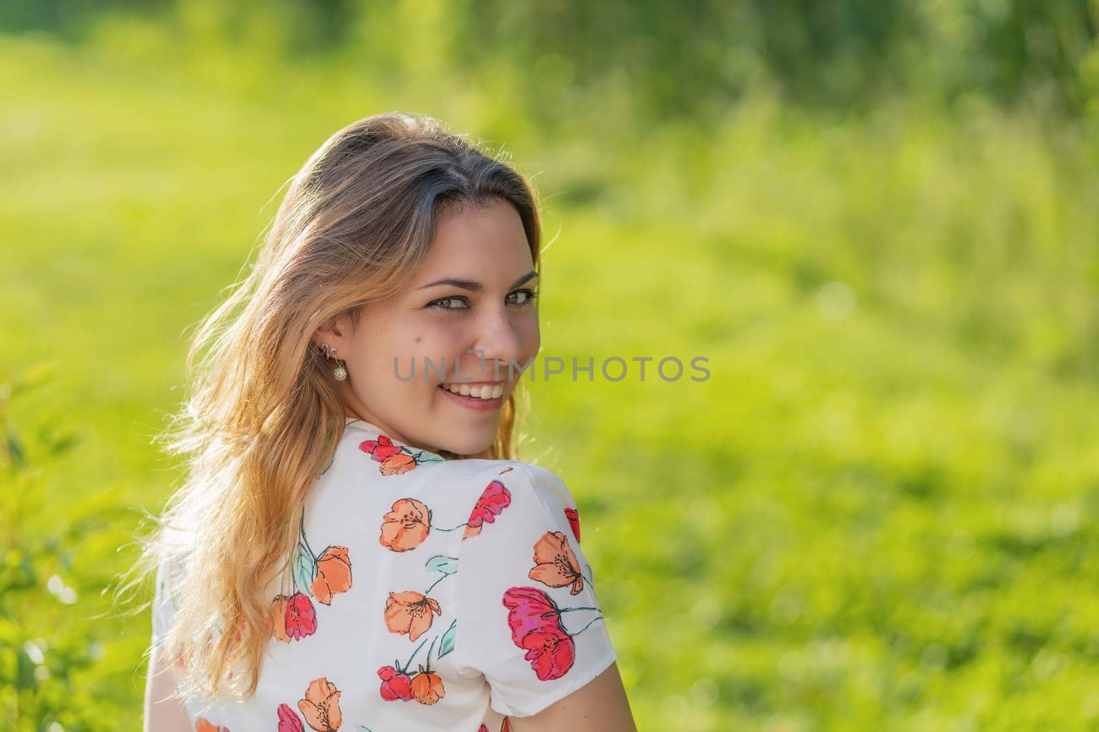 Atractive beautiful  young woman is smiling over her shoulder at the camera.  Horizontally.