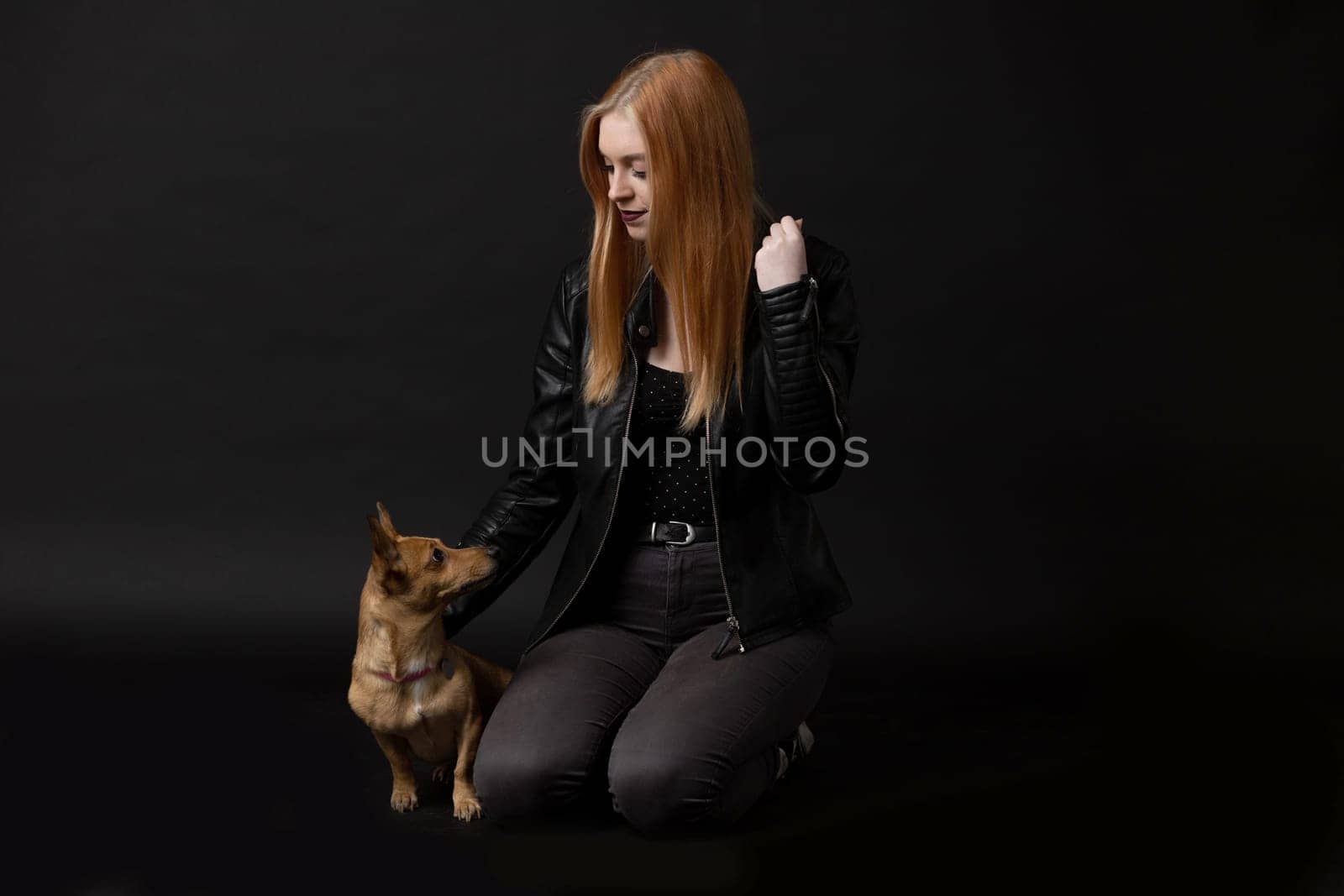 Studio portrait of beautiful young woman together with her dog. Horizontally.