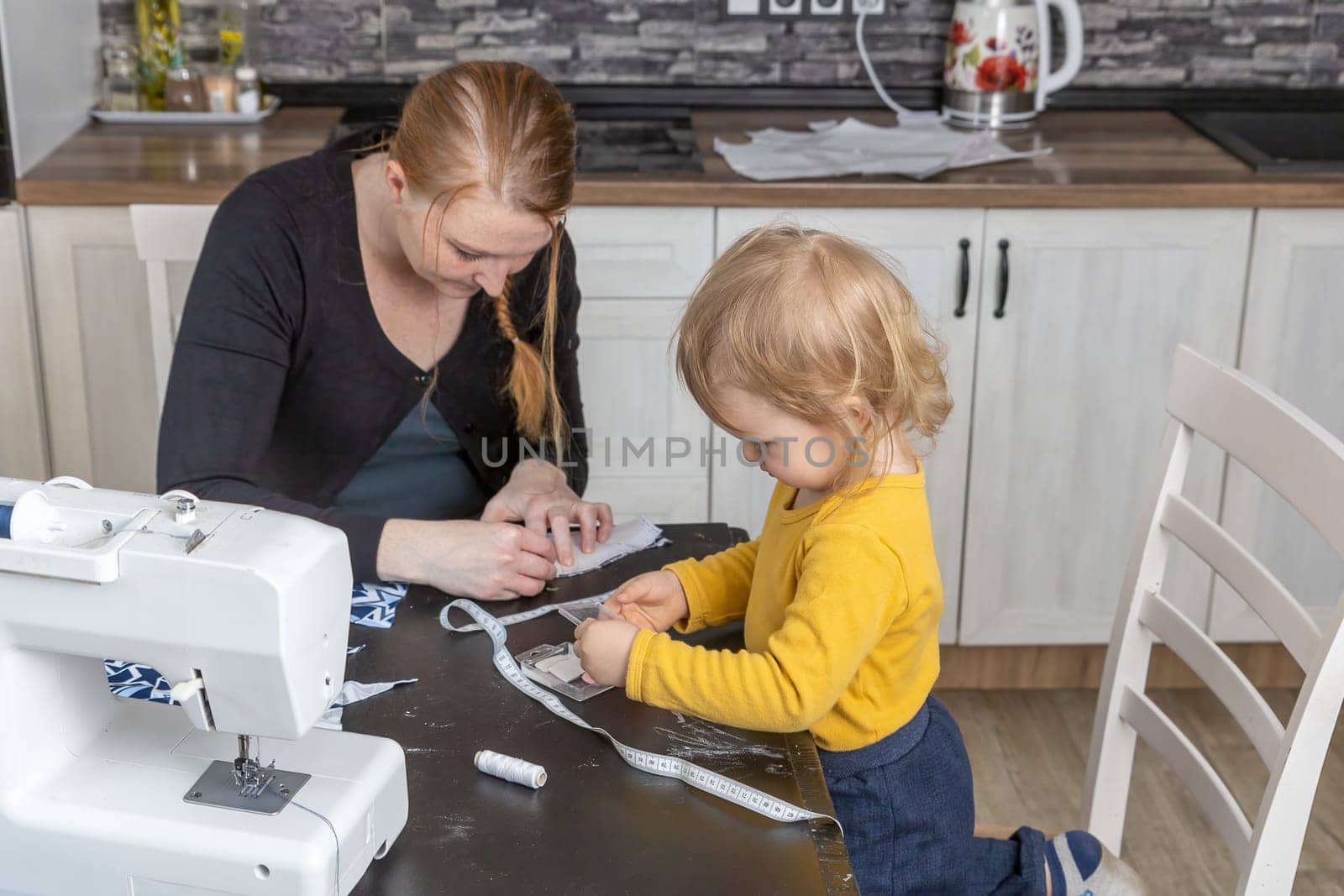Little son helps his mother in home sewing. Horizontally.