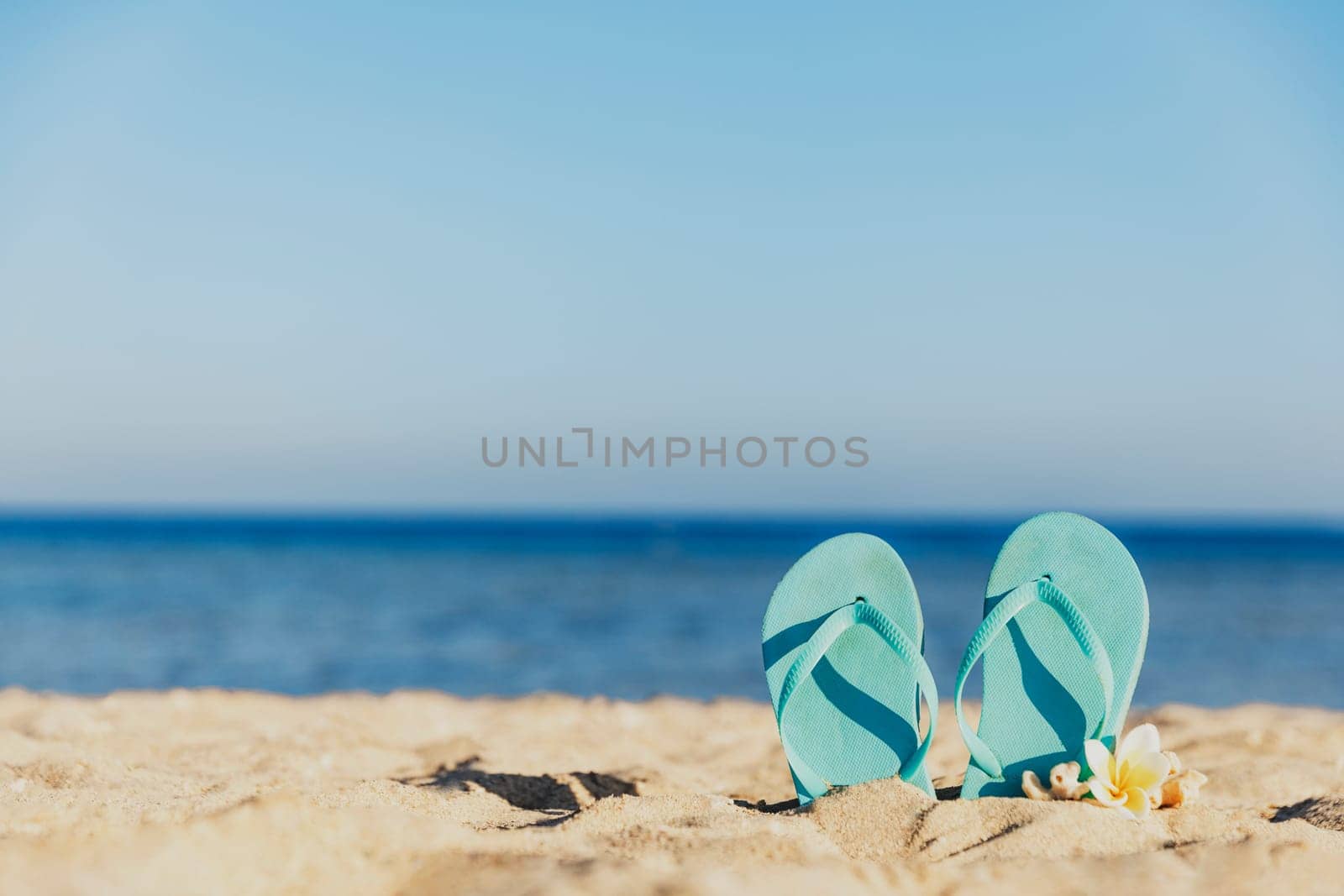 Flip flops stuck in the sand on a sandy beach by the sea or ocean. Travel or vacation concept in hot countries in summer or winter. High quality photo