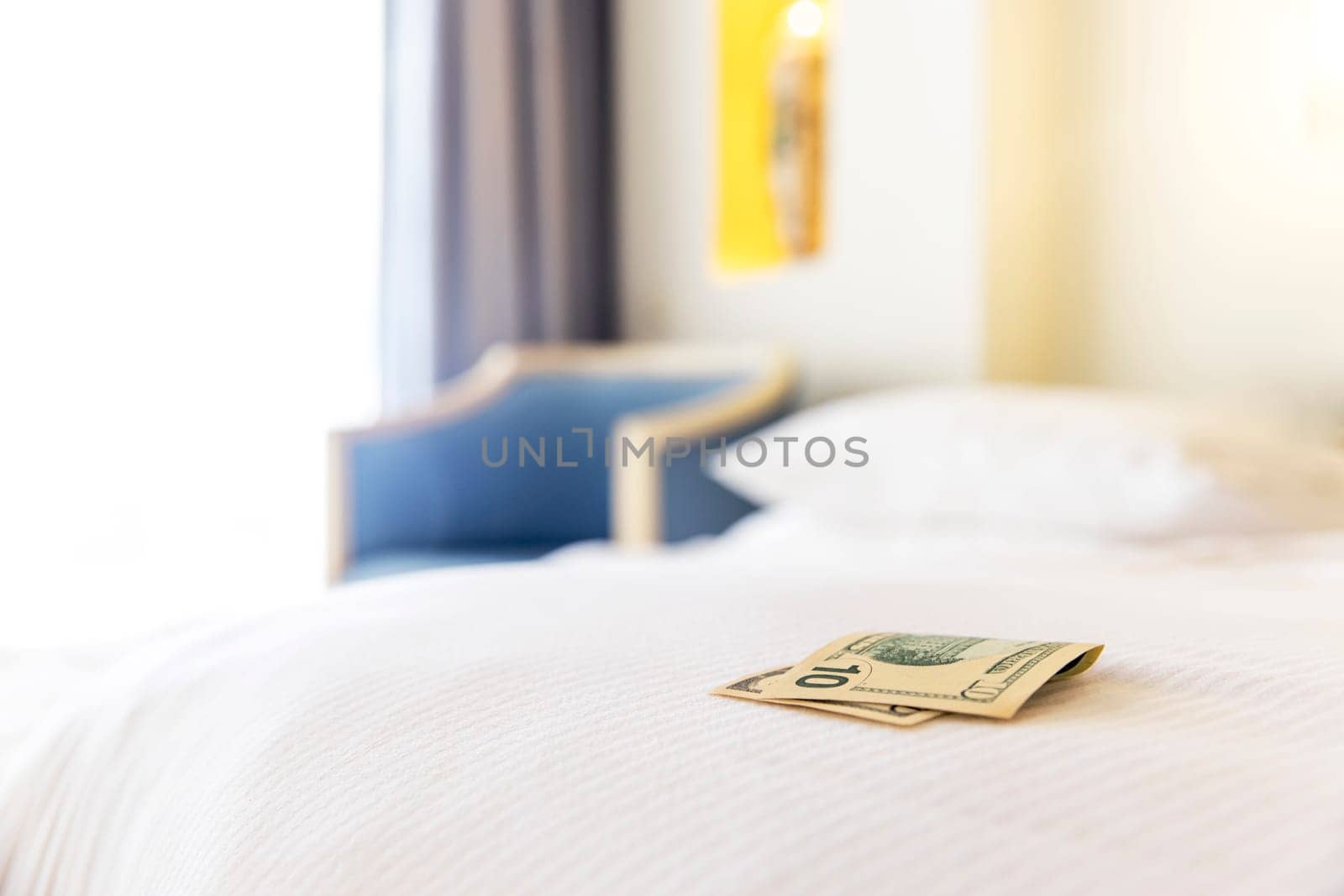Traditional tips is laying on the corner of the bed in hotel room. Dollar or euro money tips to thank the room cleaner for good service. Grateful vacationers at the Egypt resort. High quality photo