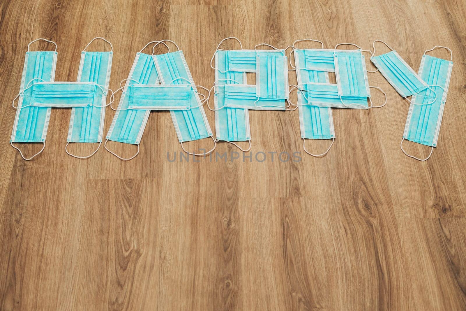 Capital Letters Happy Composed of Medical Masks on a Brown Background