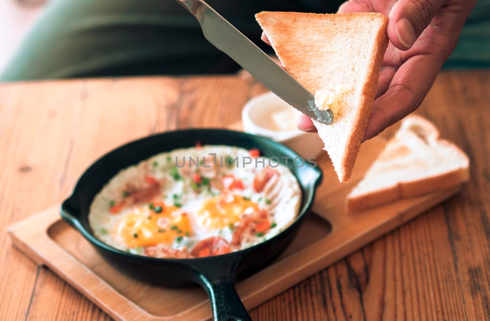 Man spreading butter on the bread with Pan Fried Egg with Toppings