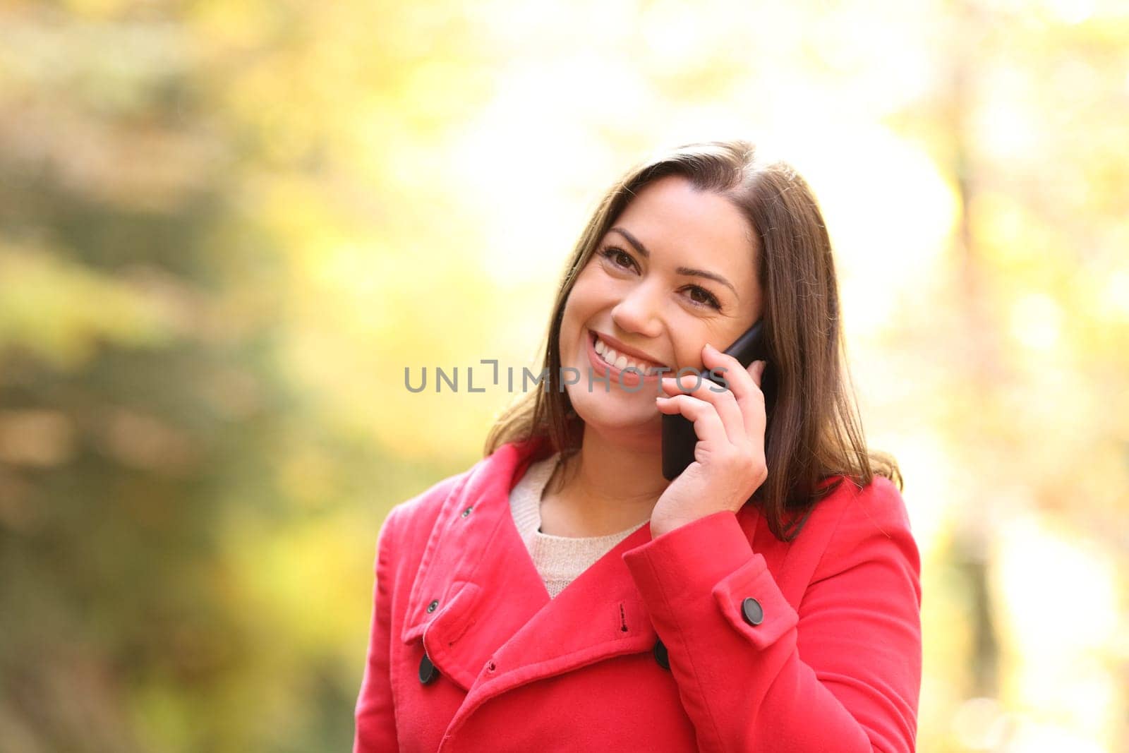 Happy woman in red talking on phone in winter