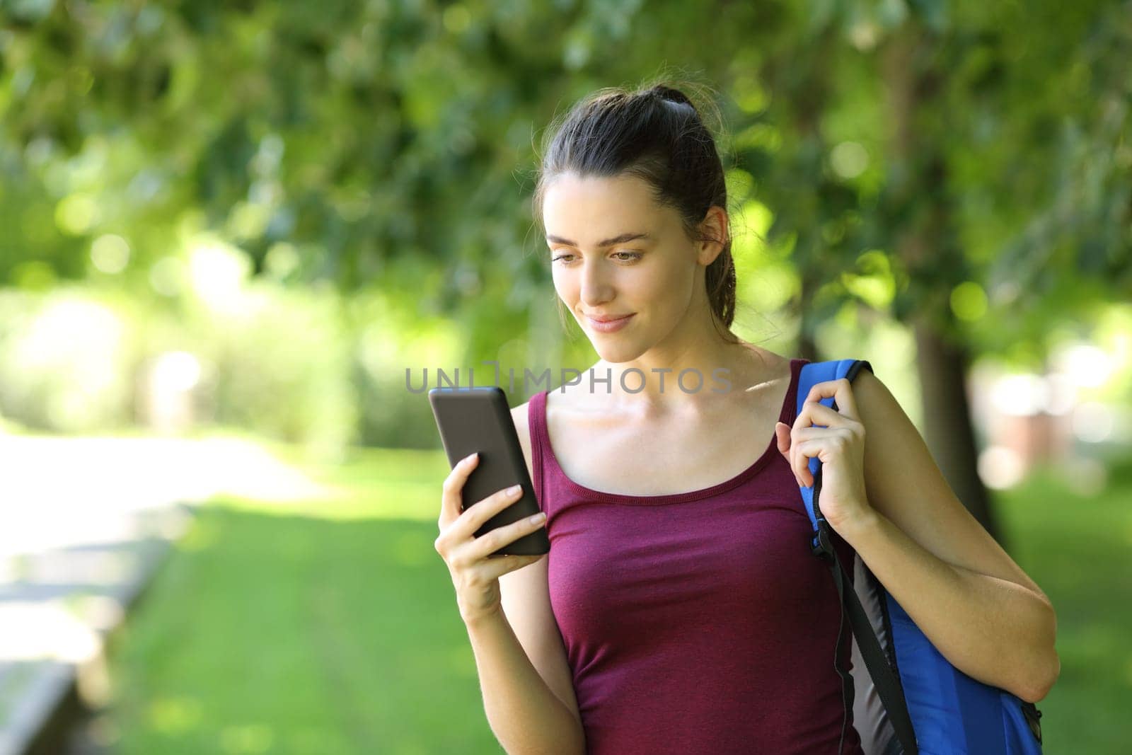 Student walking checking phone in a park