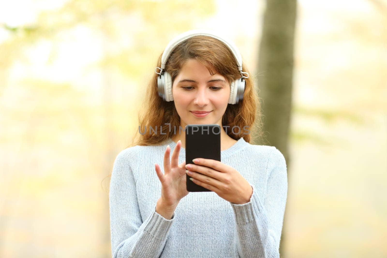 Front view of a woman listening to music in a park