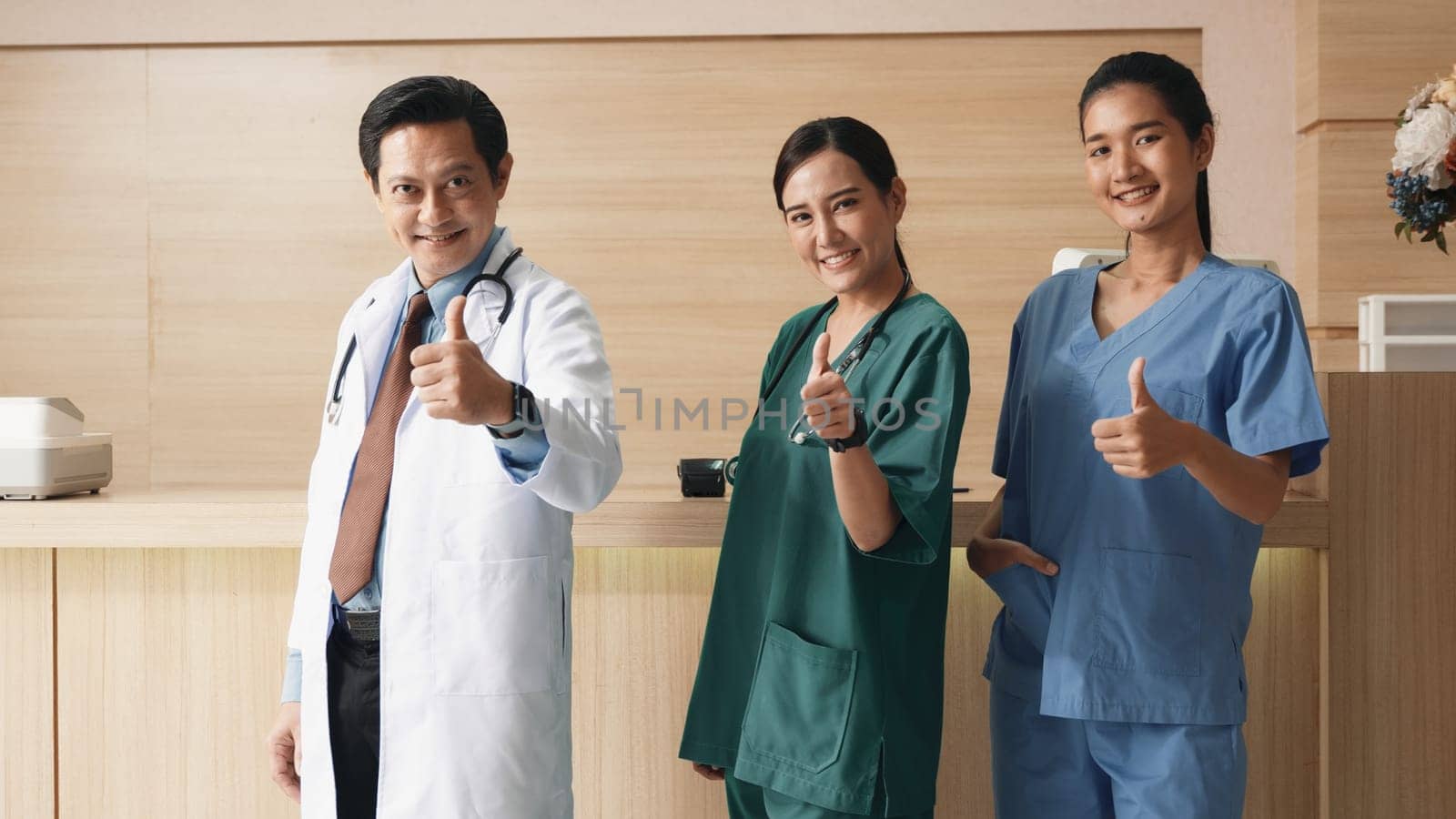 Medical personnel showing thumbs up and bandage with plaster on arm after getting Covid-19 vaccine, happy nurse woman and man standing at hospital, Covid-19 vaccination concept
