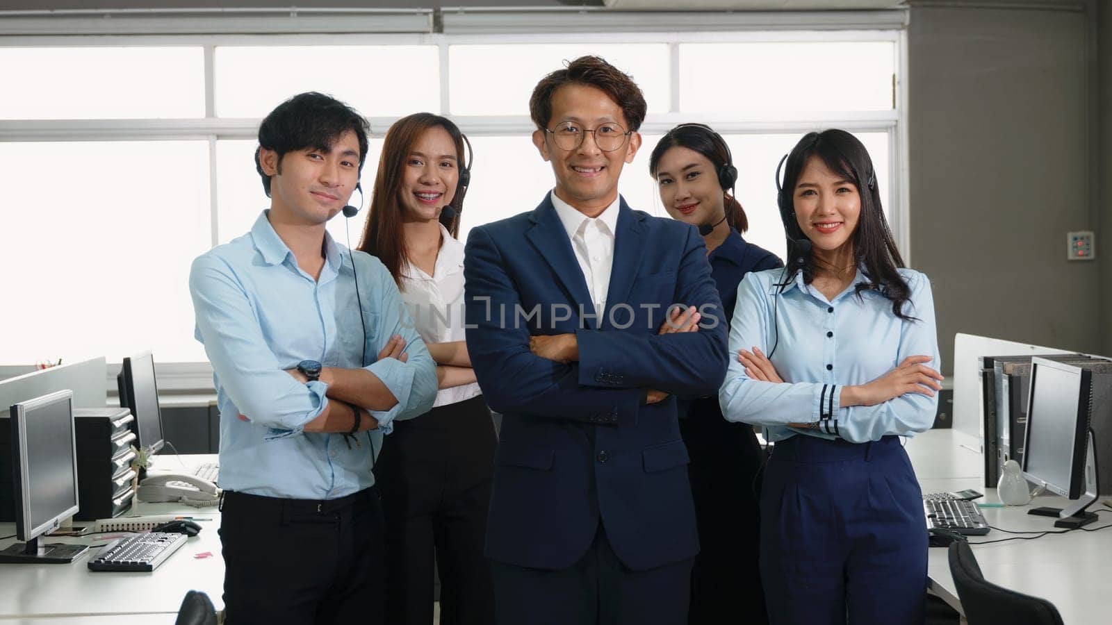 Businessman leader smiling in formal suit glasses standing smart with his arms crossed in an office workplace, portrait of happy young male boss manager or CEO look at camera