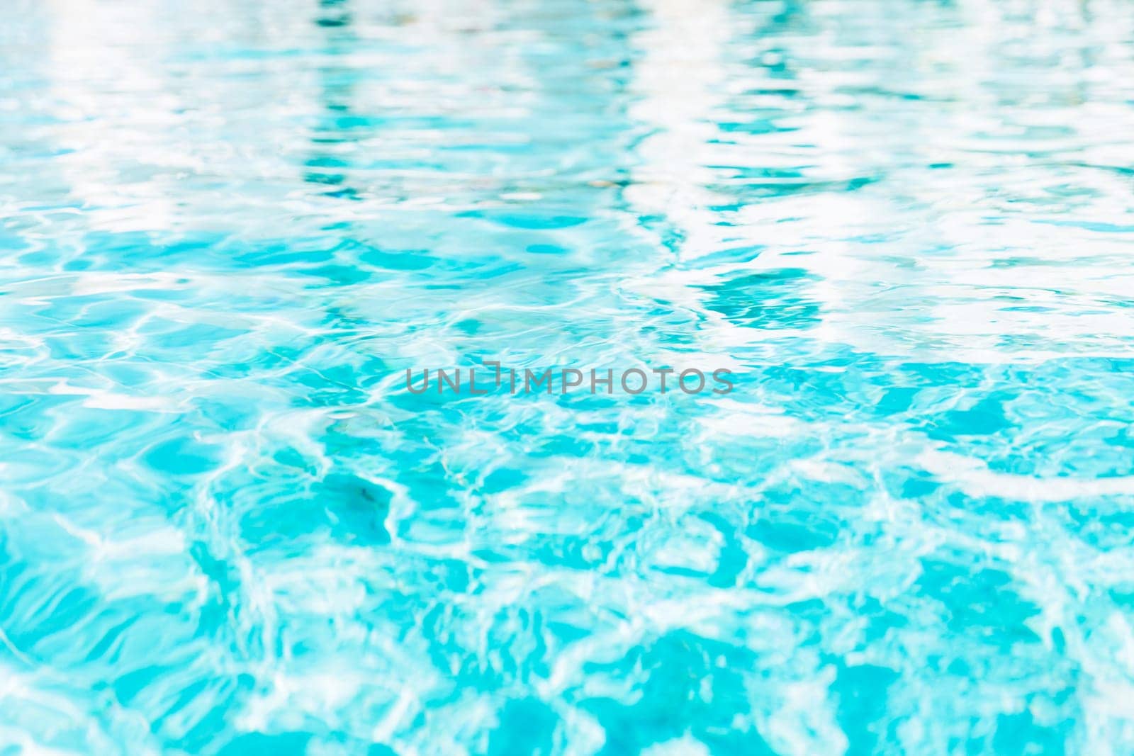 Vibrant blue white swimming pool ripped water surface with waves and nice sun sparkles. Conceptual abstract texture background. Travel or vacation summer concept. High quality photo
