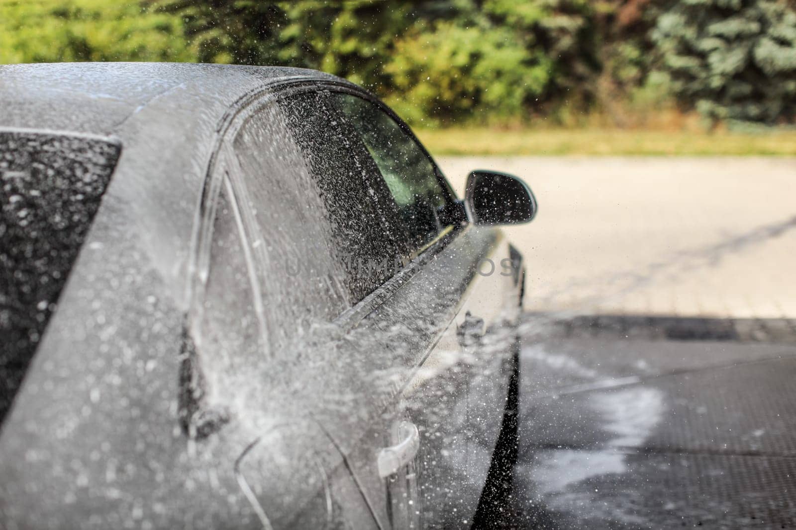 Car being washed at carwash. Focus only on flying drops of shampoo and foam for dynamic effect.