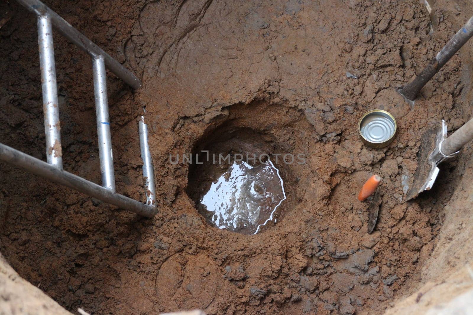 groundwater has appeared at the bottom of a deep round well with hand tools