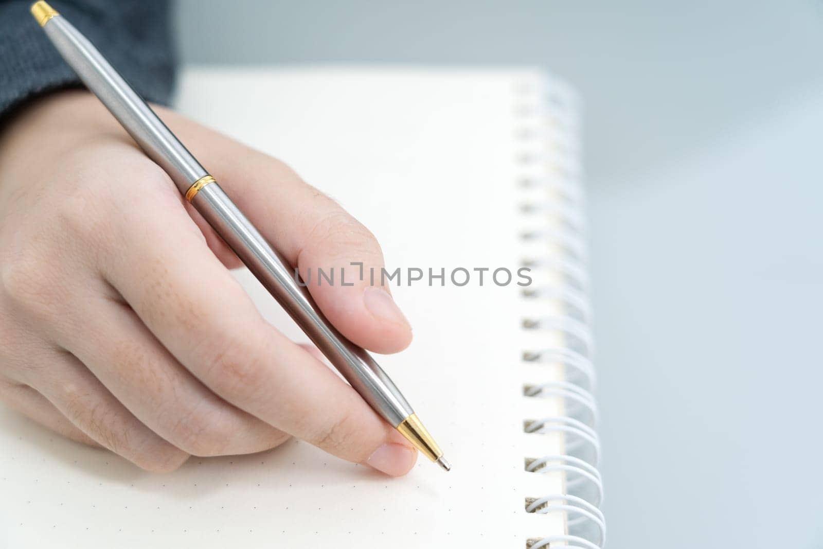 Businesswoman writing on notebook in office, hand of woman holding pen with writing notebook on desk