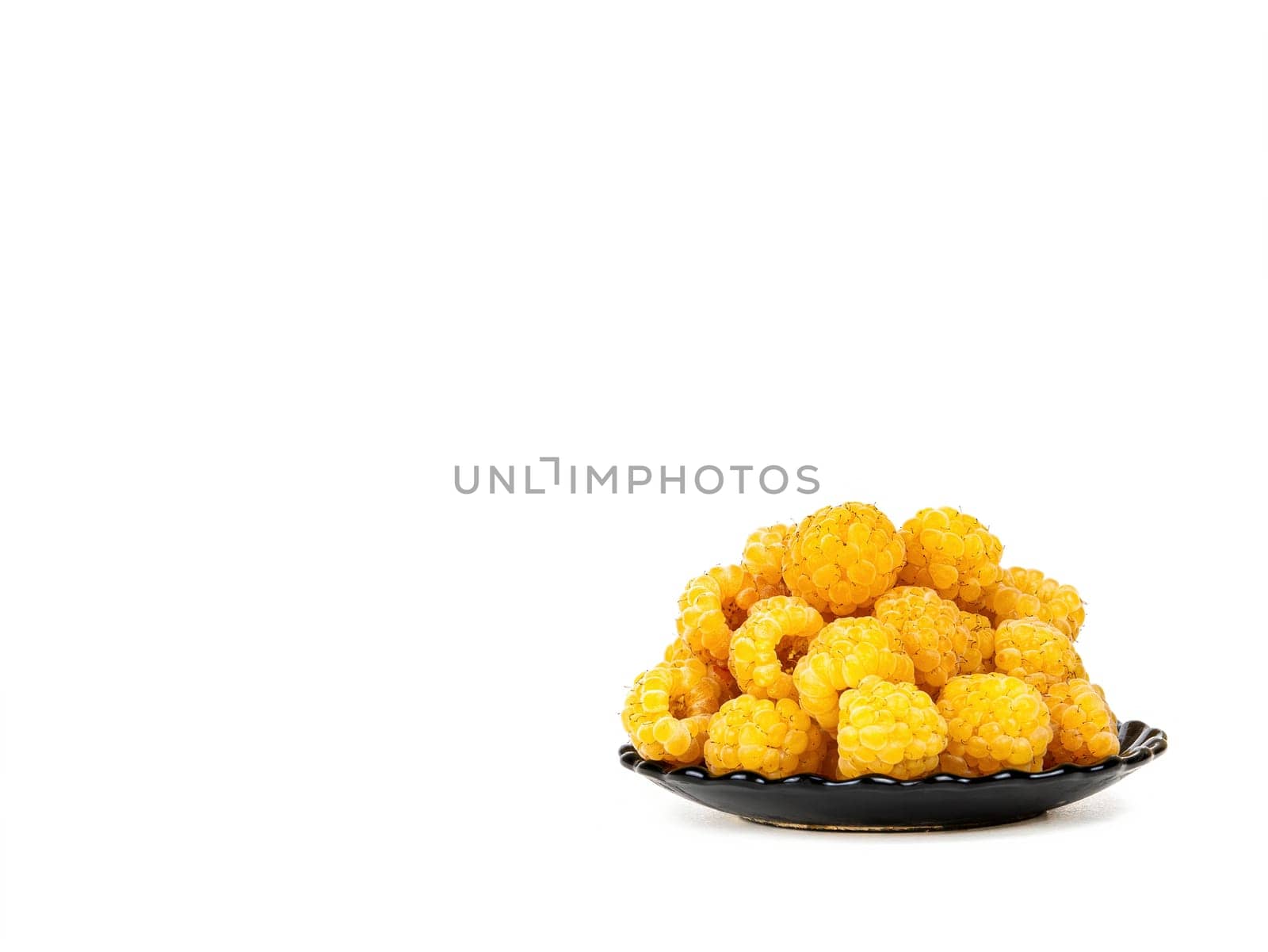 Berries of yellow raspberries in a black plate on a white background. Yellow raspberries. Fruit berries. Harvesting. Fruit dessert. Healthy eating. White background. Shop window.