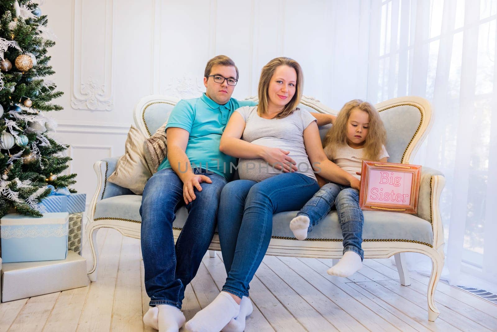 Family portrait near christmas tree. Pregnant woman.