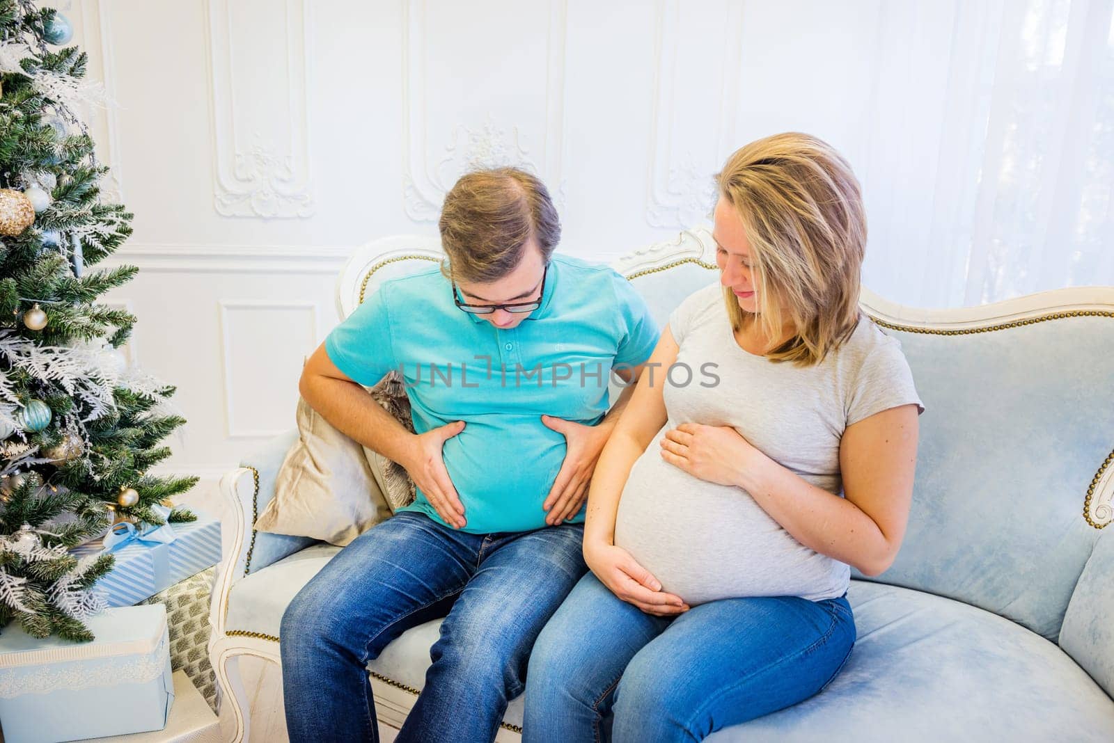 Family portrait near christmas tree. Pregnant woman.