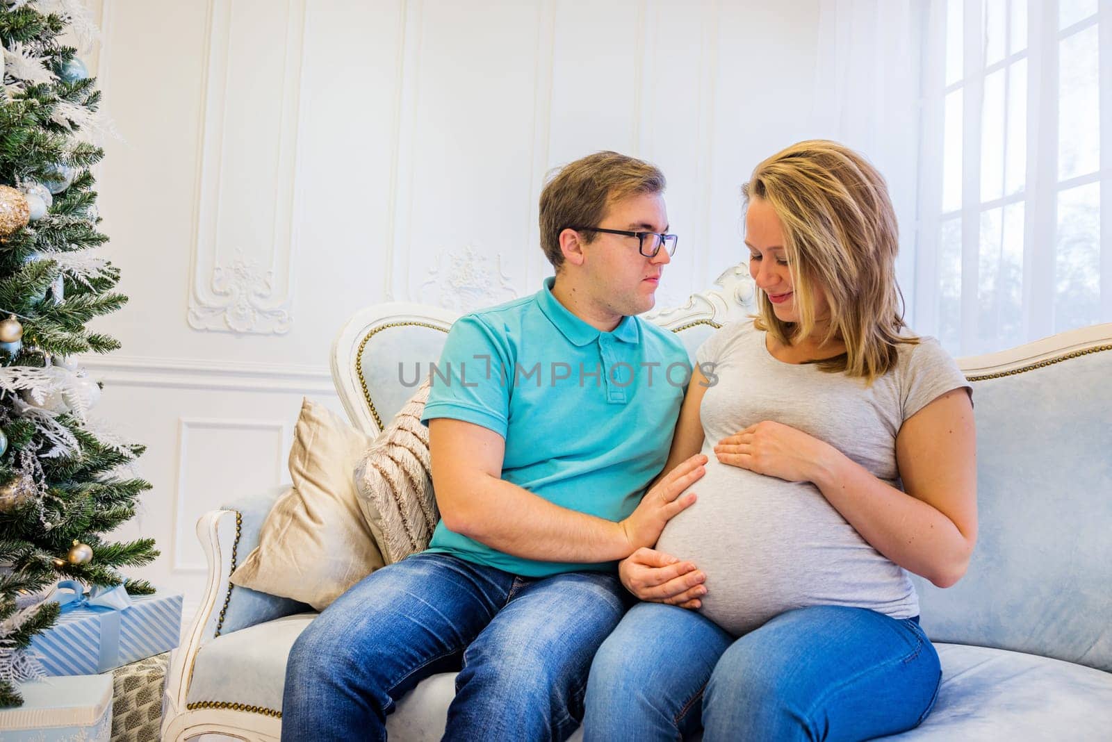 Family portrait near christmas tree. Pregnant woman.