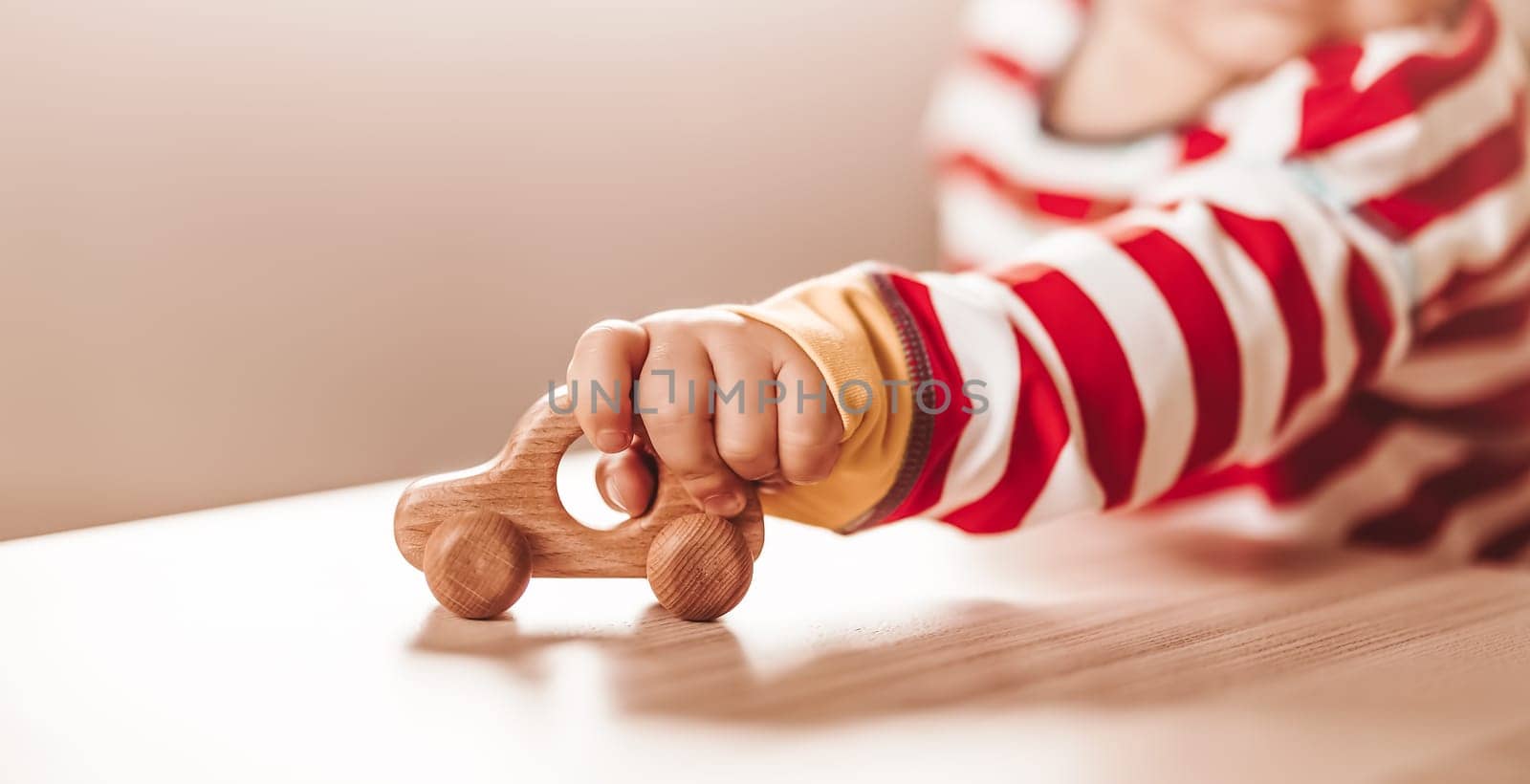 Little boy playing with wood car indoor. Concept of family travel and buying a new automobile.