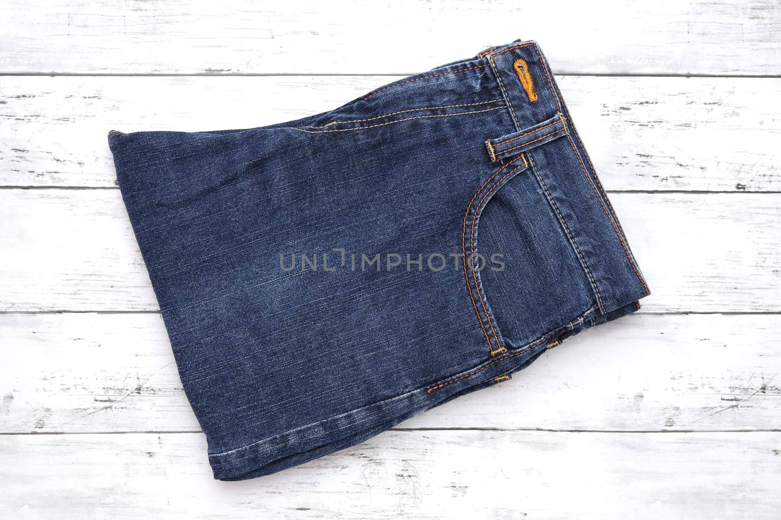 Folded blue jeans on white wooden background, denim folded on wooden background
