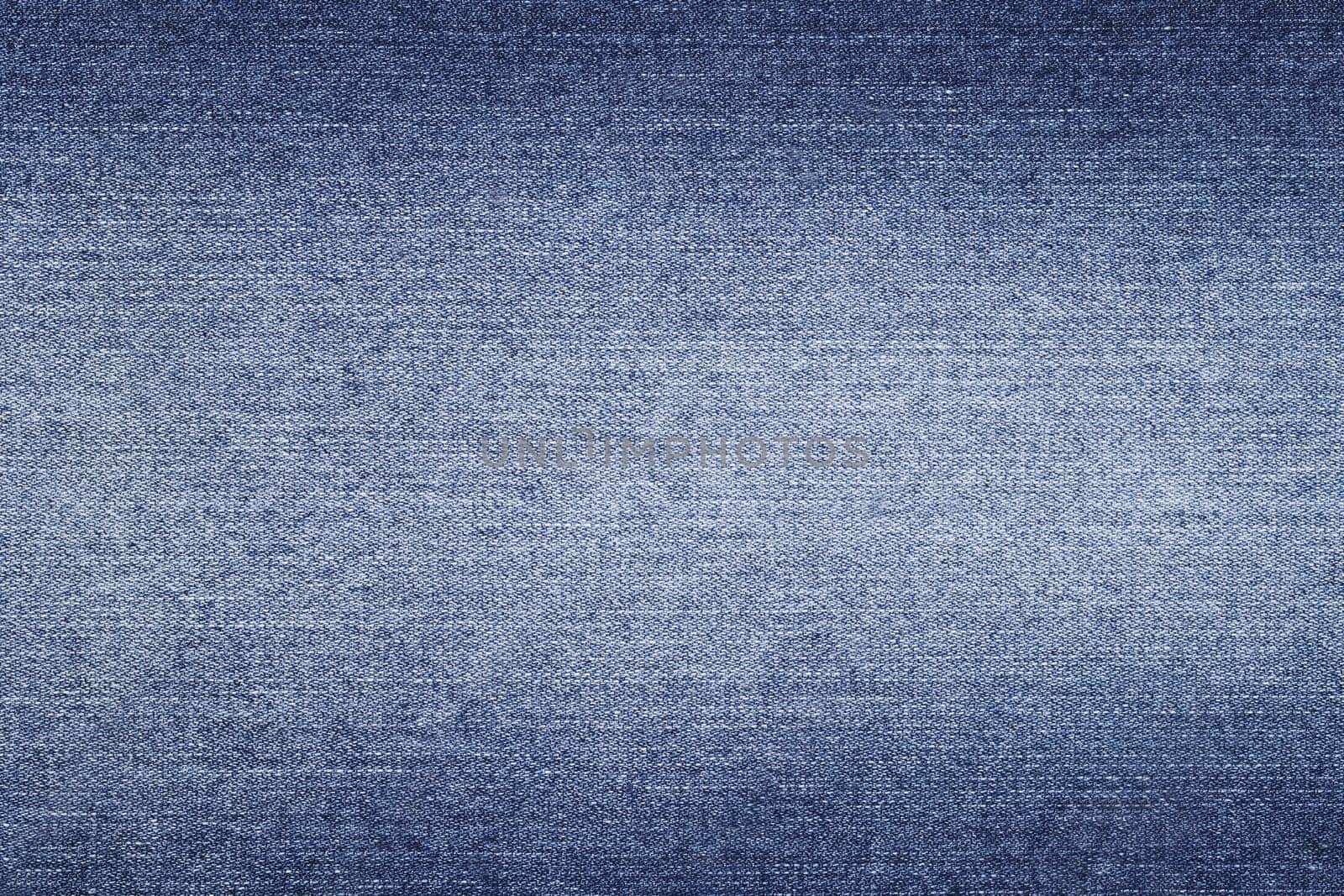Denim background in blue fabric with faded. Blue discolored jeans close-up