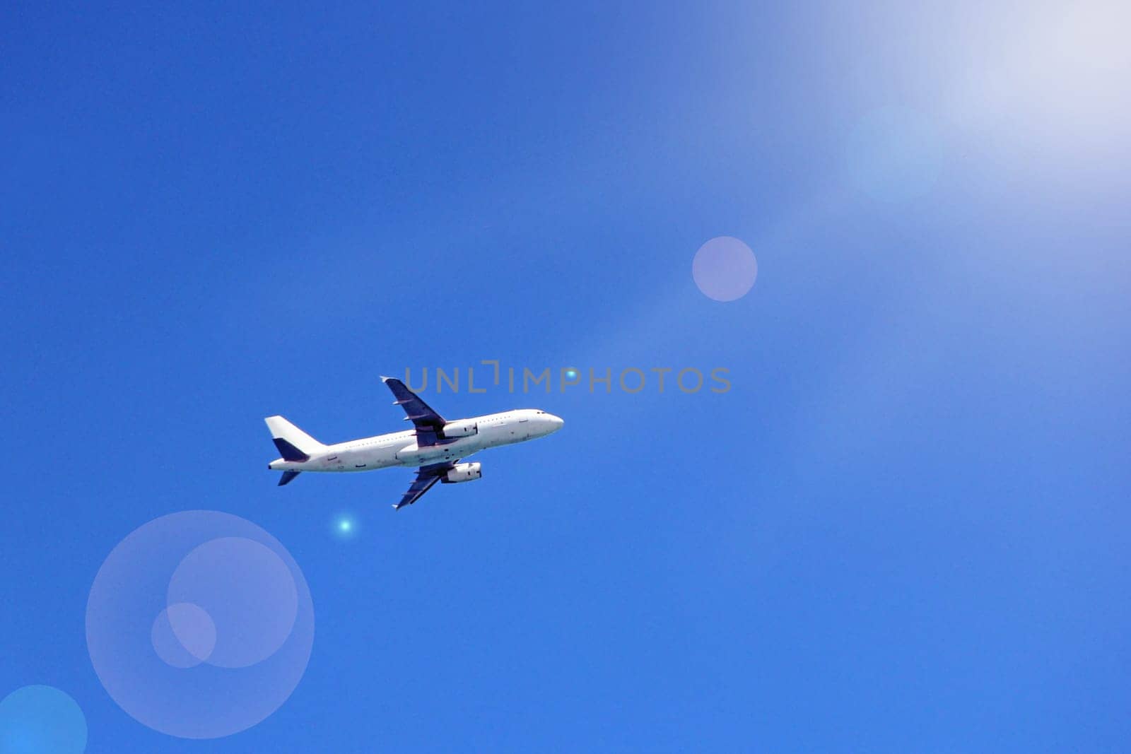 Plane flying high in blue sky with sunny rays. Air liner flying in blue sky. Airplane seen in heaven. Aerial panorama with aircraft in cloudless sky. Flying air liner. Passenger airliner in flight