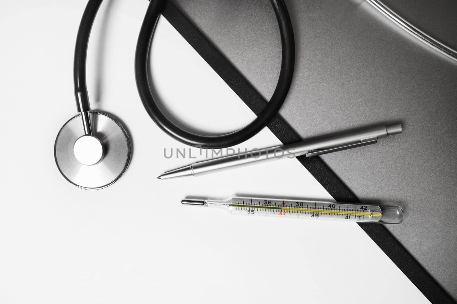 Medical stethoscope, thermometer and pen. Flat lay.