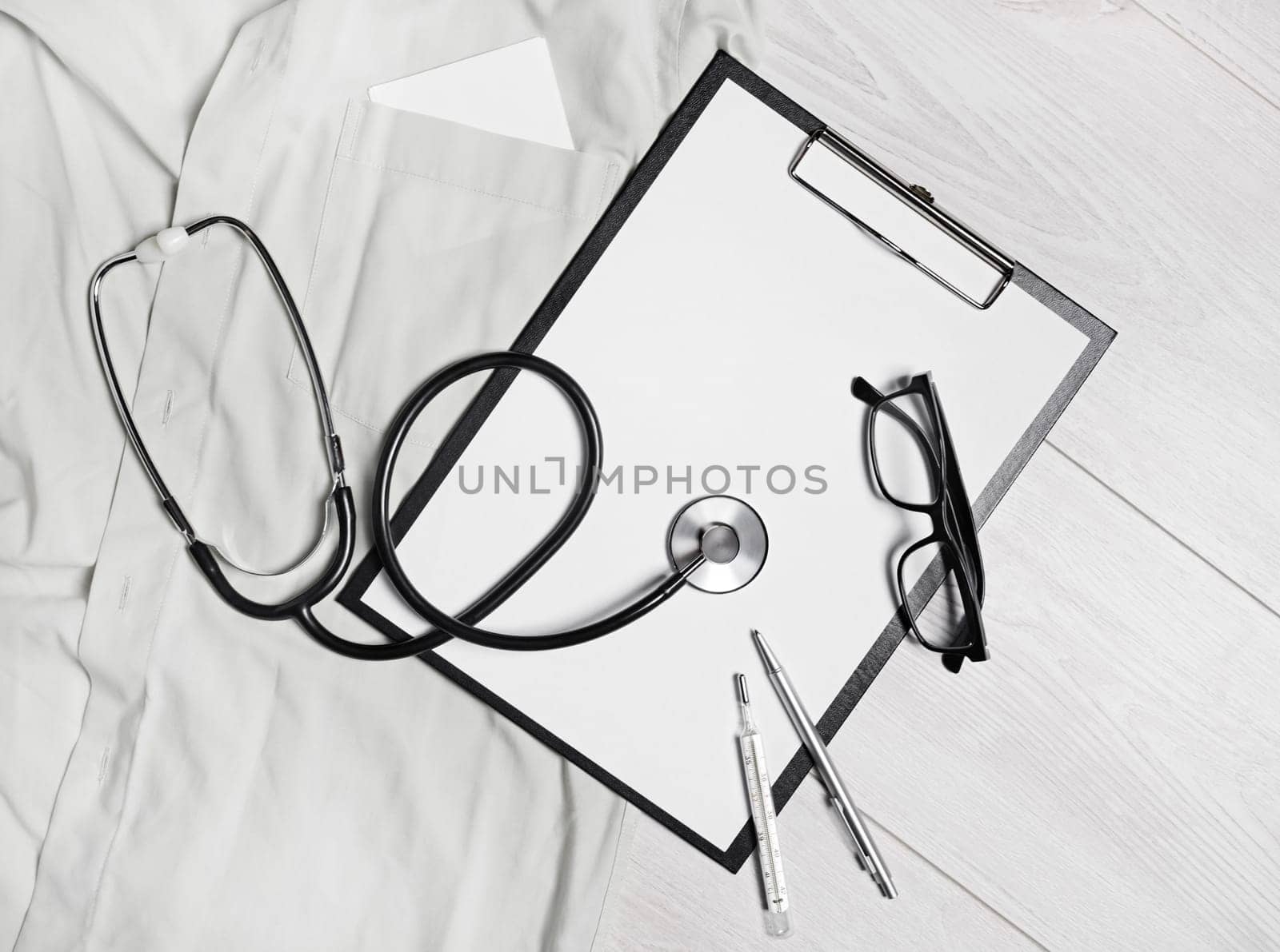 Medical still life. Blank clipboard, stethoscope, glasses, thermometer and pen. Flat lay.