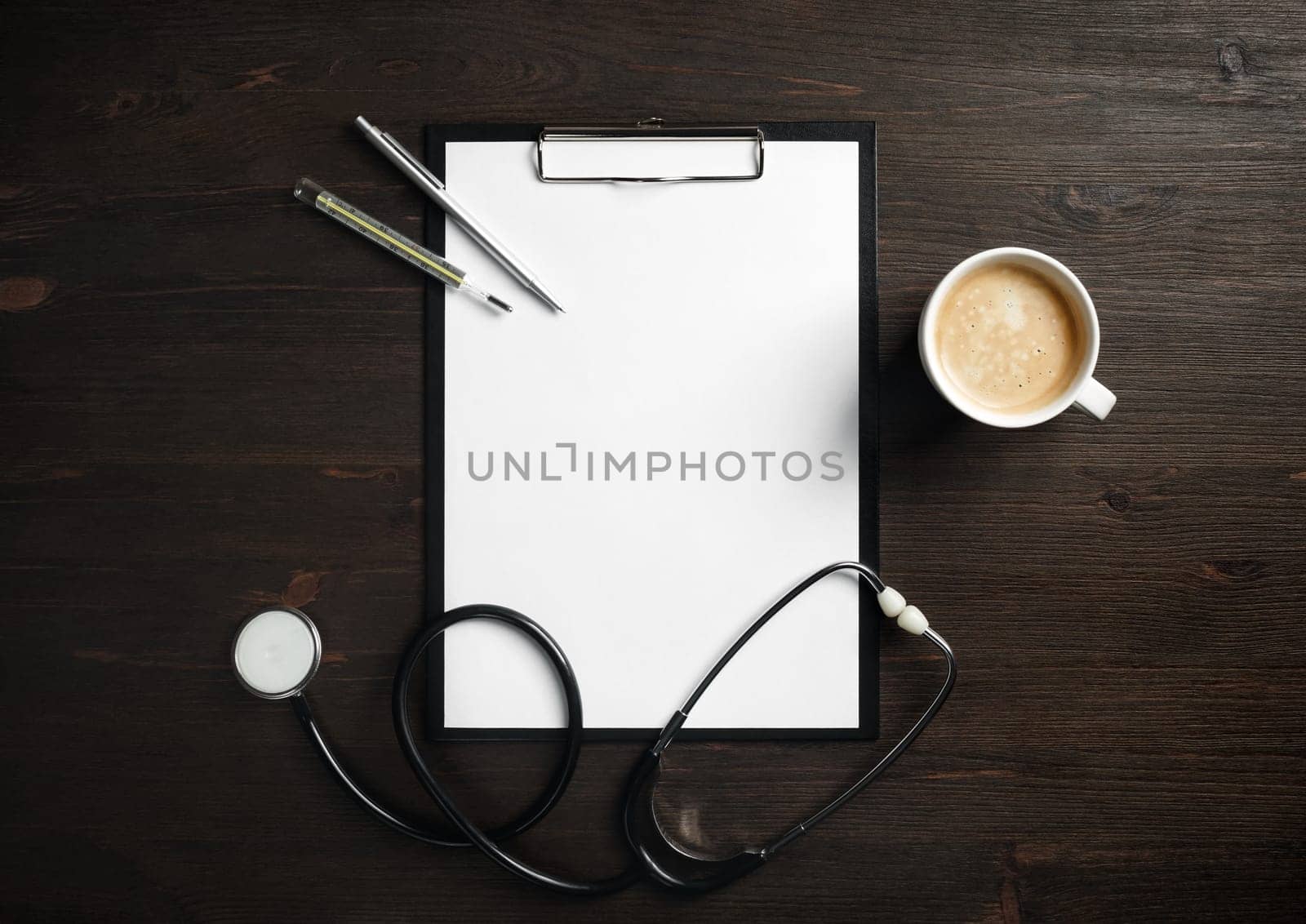 Blank medical clipboard, stethoscope, badge, thermometer, pen and coffee cup on wooden background. Flat lay.