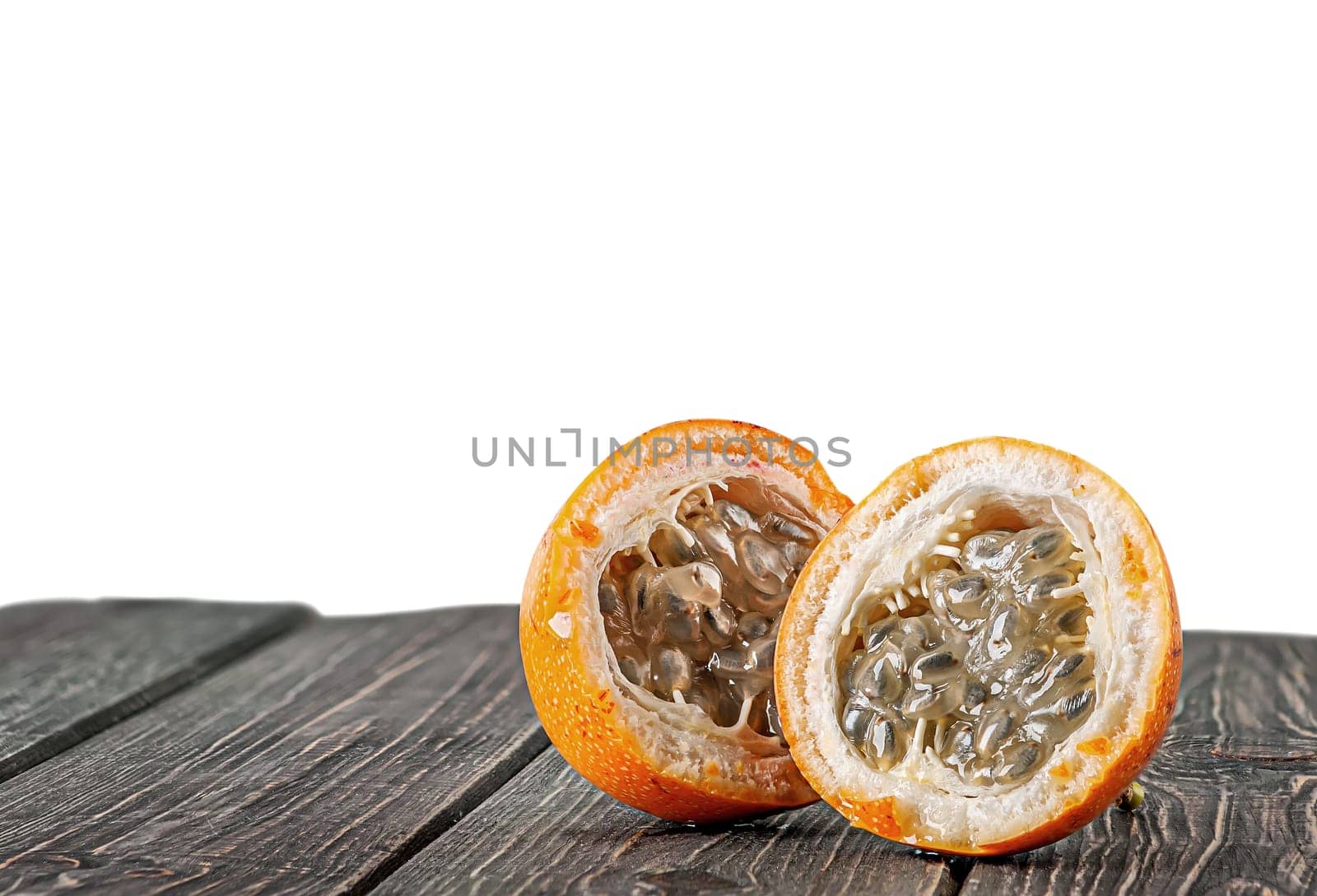 Two halves of tamarillo on wooden table isolated on white background