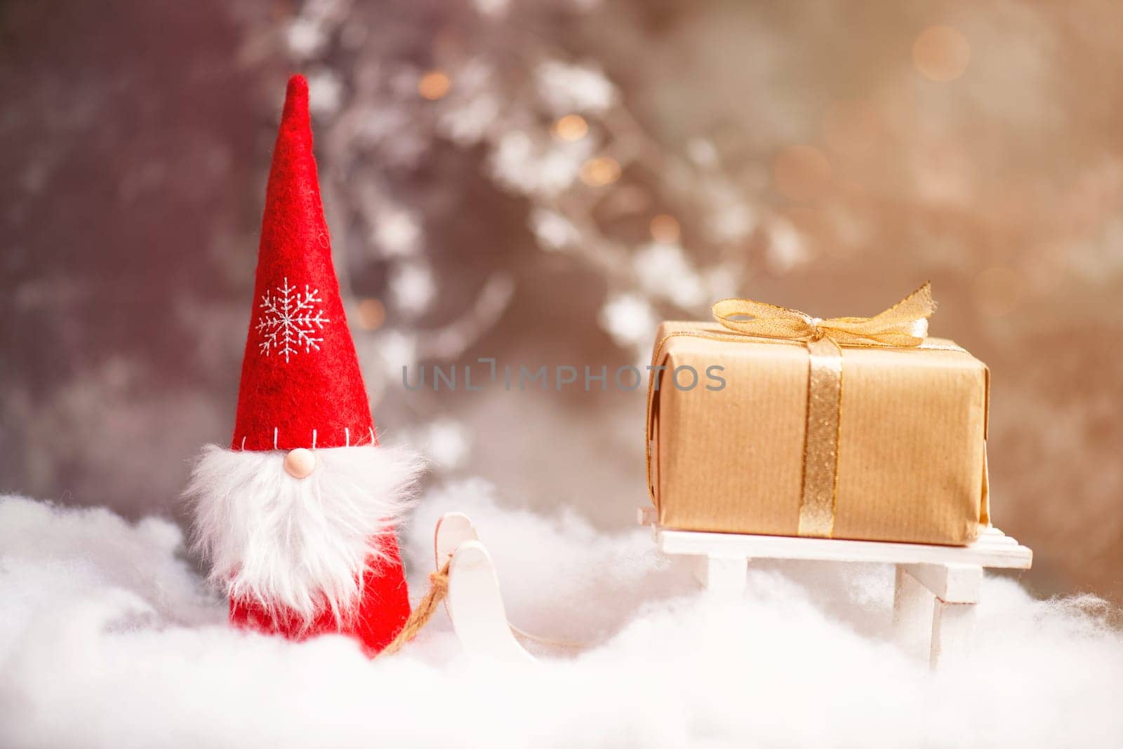 Christmas gnome greeting card with bokeh lights and snow, winter season, gift on the sledge